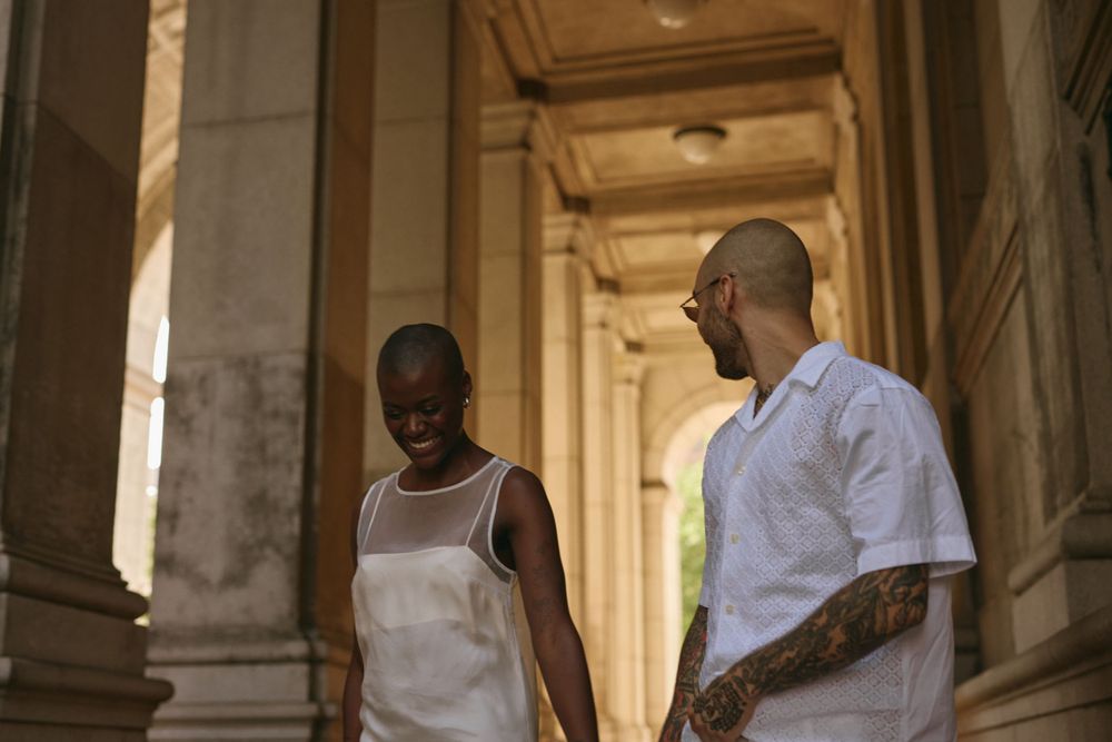 Two people standing in warm sunlight between elegant architectural columns.