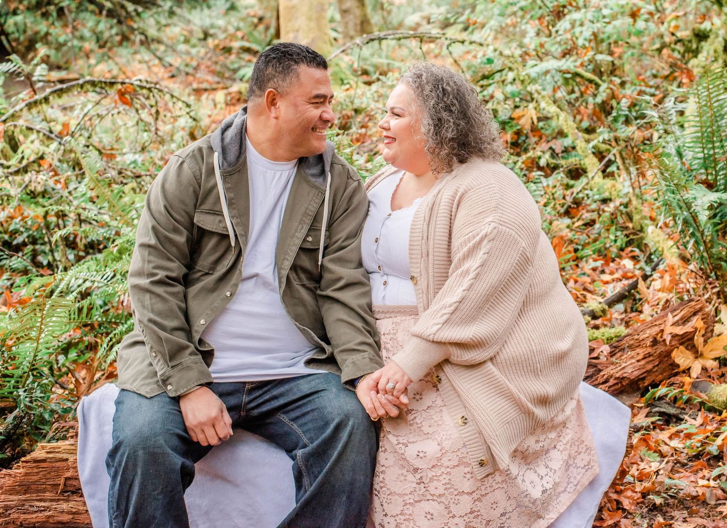 Romantic couple sharing tender moments on wooden bench in forest setting.