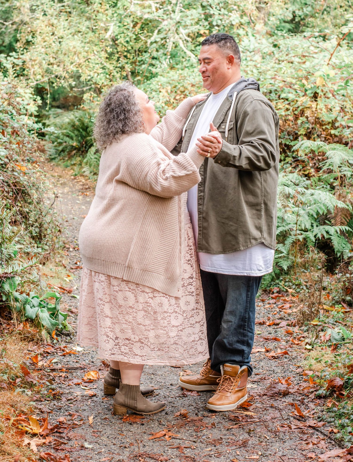 Family members sharing heartfelt hugs on a forest trail covered in autumn leaves.