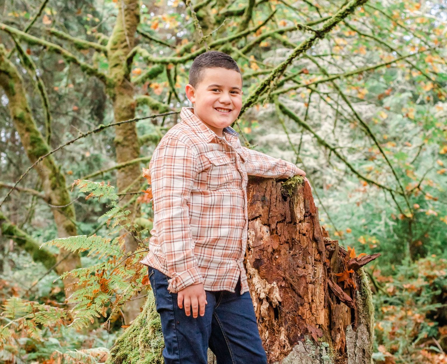 Playful outdoor autumn portraits near a weathered tree stump.