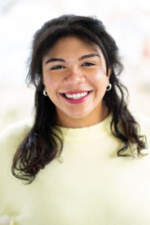 Close-up portrait with bright genuine smile against light background.