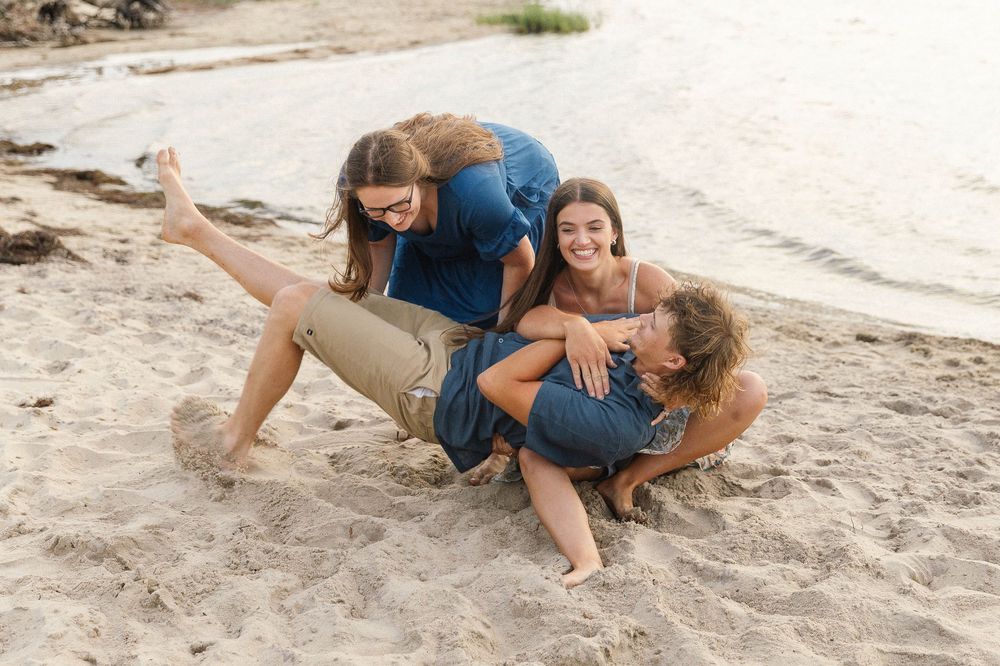 Playful moment captured of people rolling in the sand at the beach.