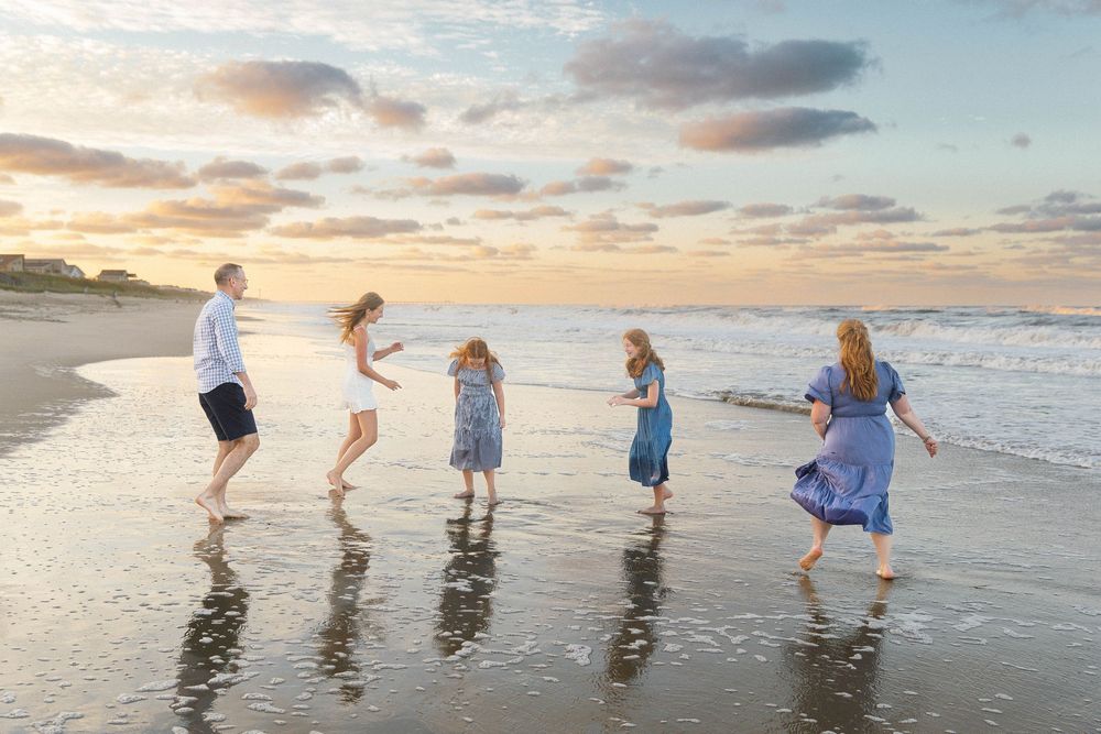 Group of children playing and splashing in ocean waves at sunset on a sandy beach during summer vacation.