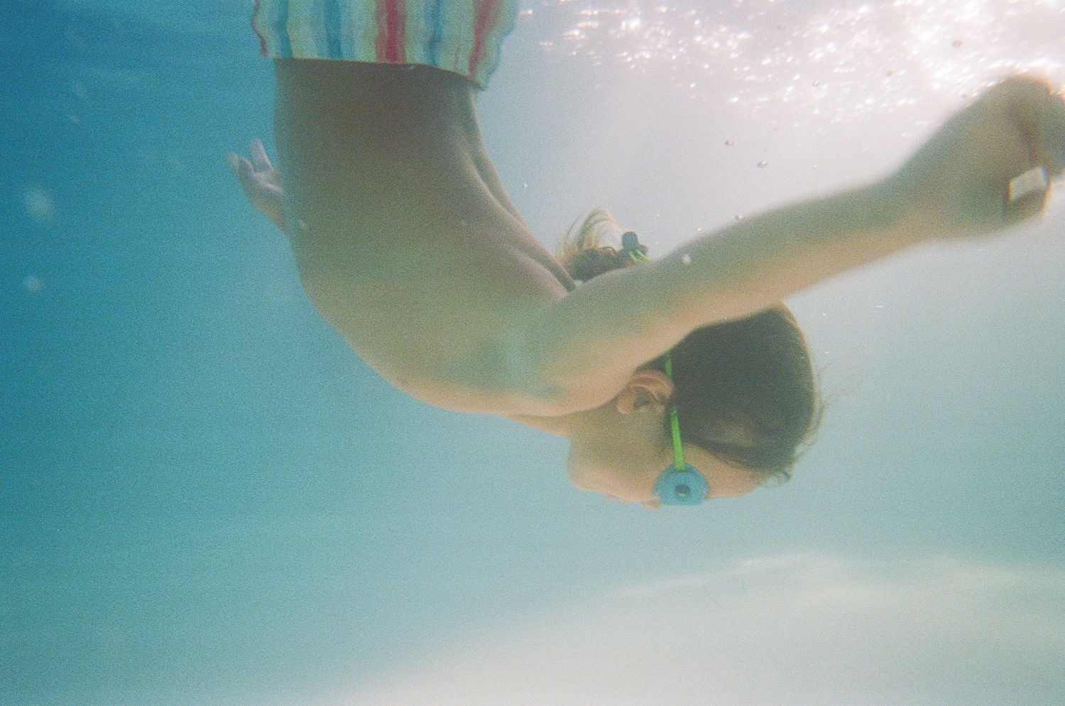 Underwater shot of a swimmer gracefully diving in crystal clear pool water.