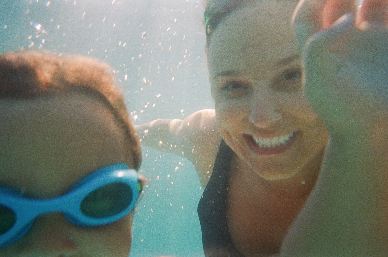 Underwater view of two swimmers taking a photo with goggles in a pool.