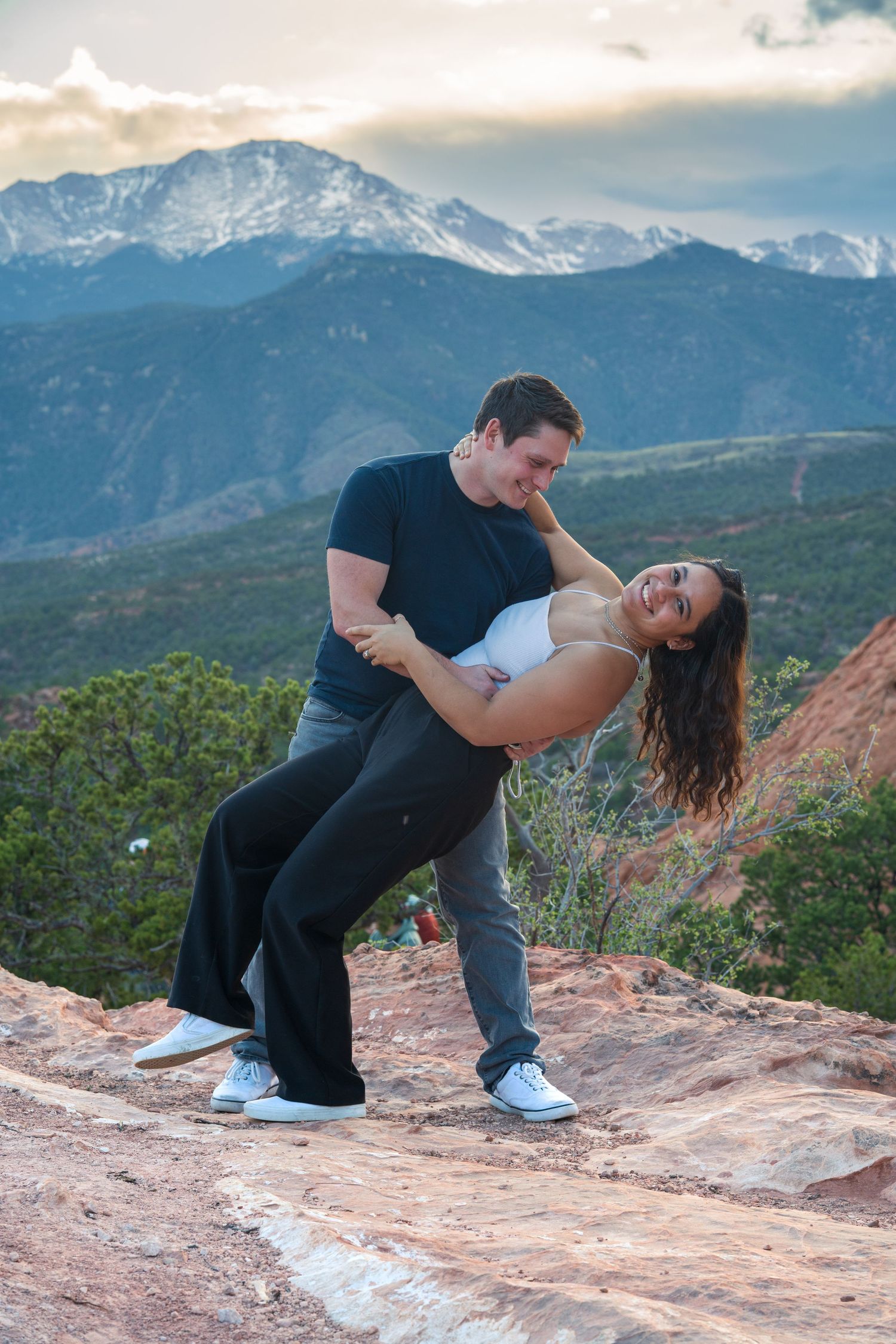 A playful dip pose on red rocks with Pikes Peak mountain range as a backdrop. garden of the gods colorado. engagement adventure session