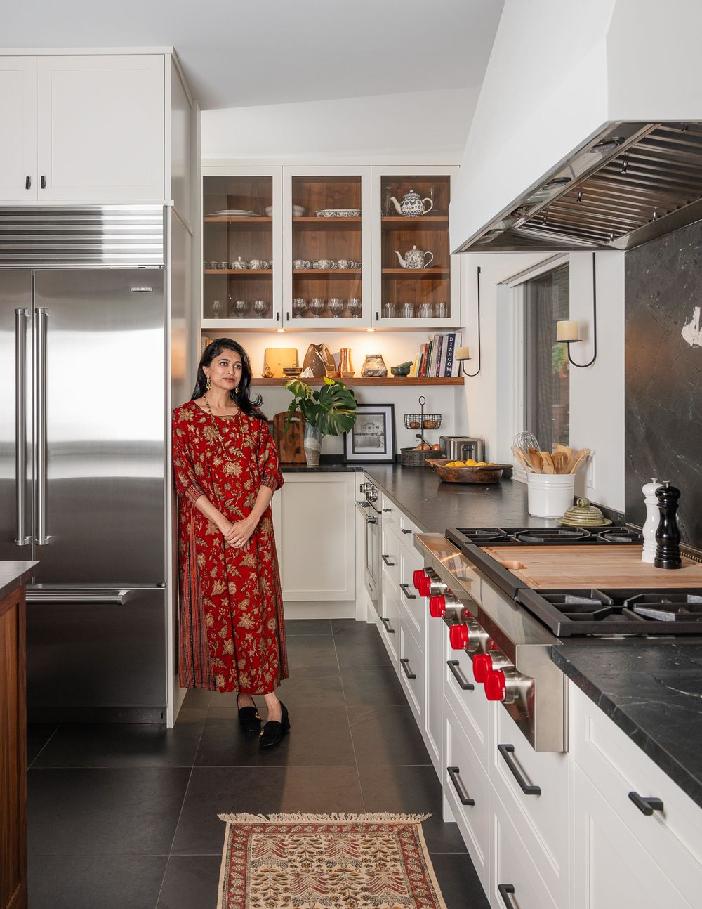 Modern kitchen with stainless appliances, white cabinets, dark countertops and a patterned runner rug.