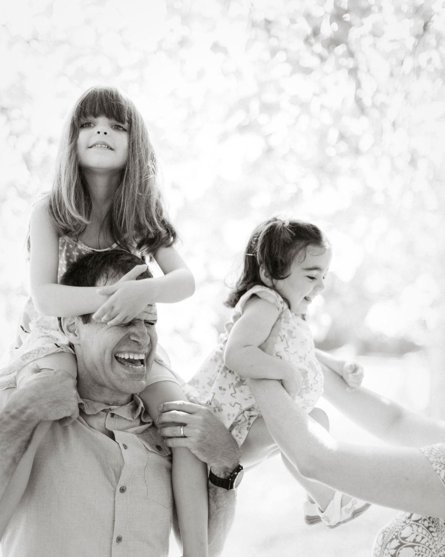 Joyful outdoor family moment captured in black and white with playful expressions.