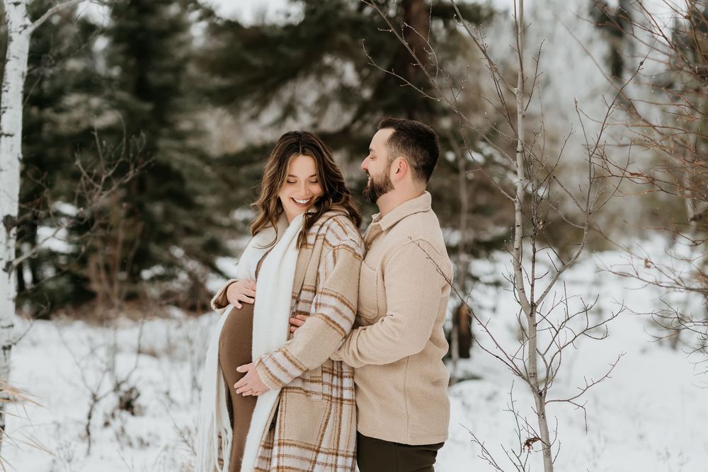 Couple in matching beige outfits share intimate moment in snowy winter forest.