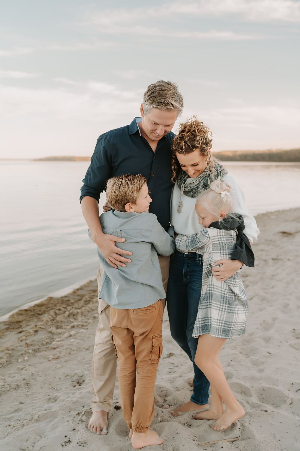 A family shares warm embraces on a sandy beach at sunset.