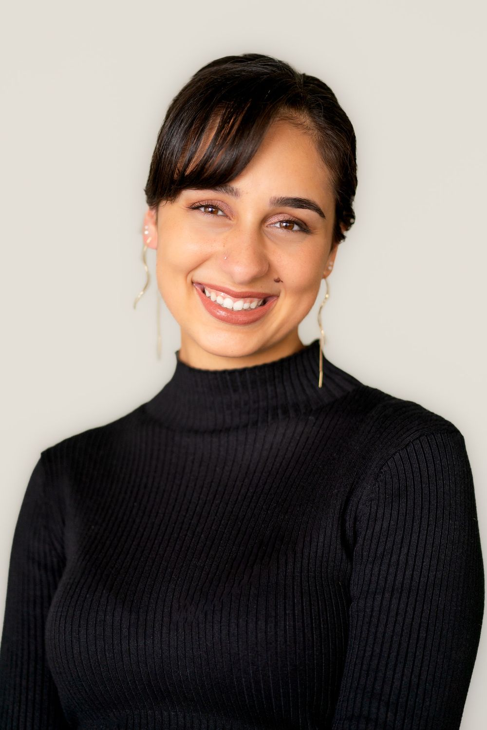 Close up portrait series of a person in a black turtleneck sweater showing different smiling expressions.