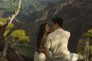 Couple enjoying a scenic mountain overlook with dramatic coastal cliffs and lush green valleys in Hawaii.