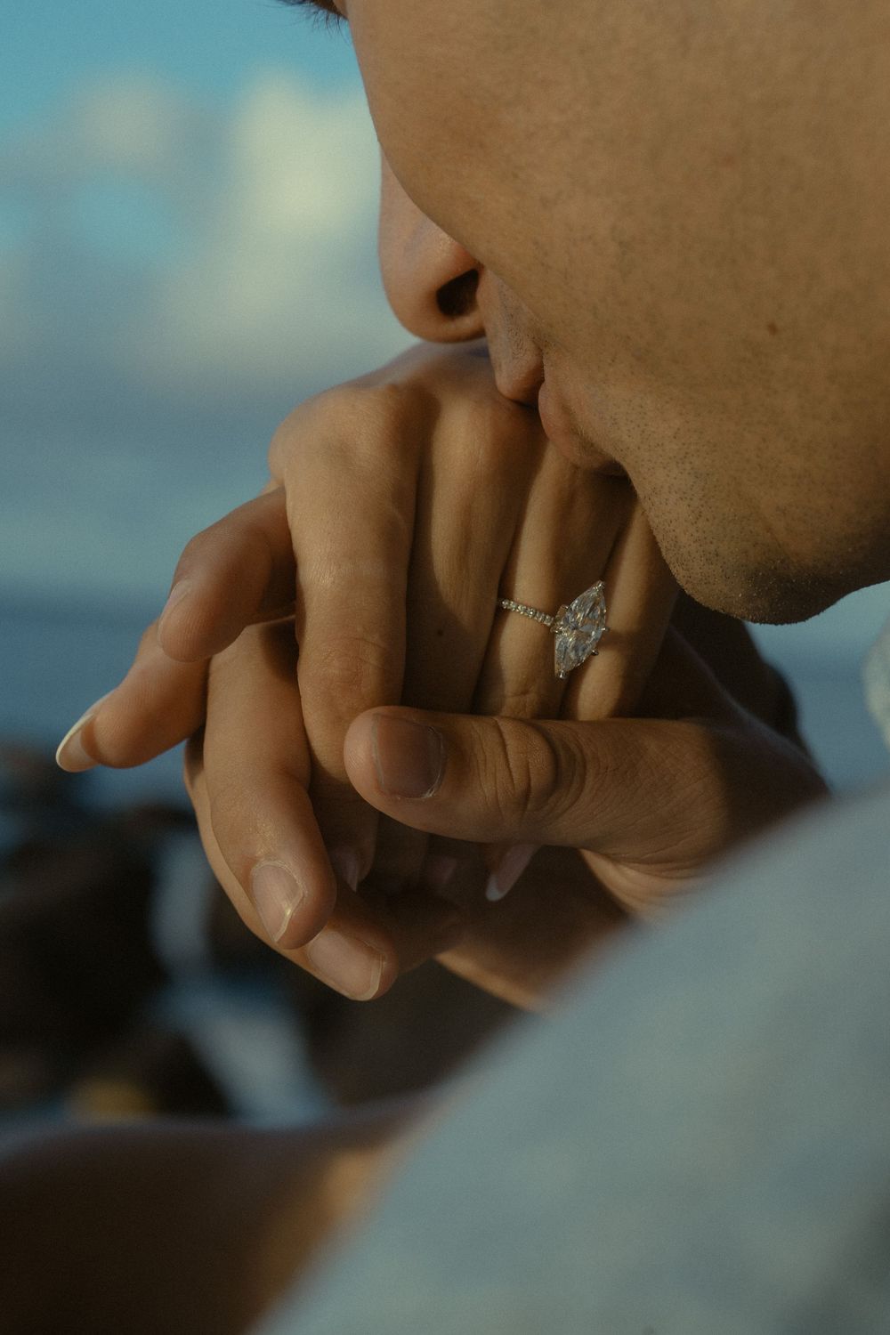 Close-up view of hands wearing a delicate butterfly ring with silver details against a blurred background.