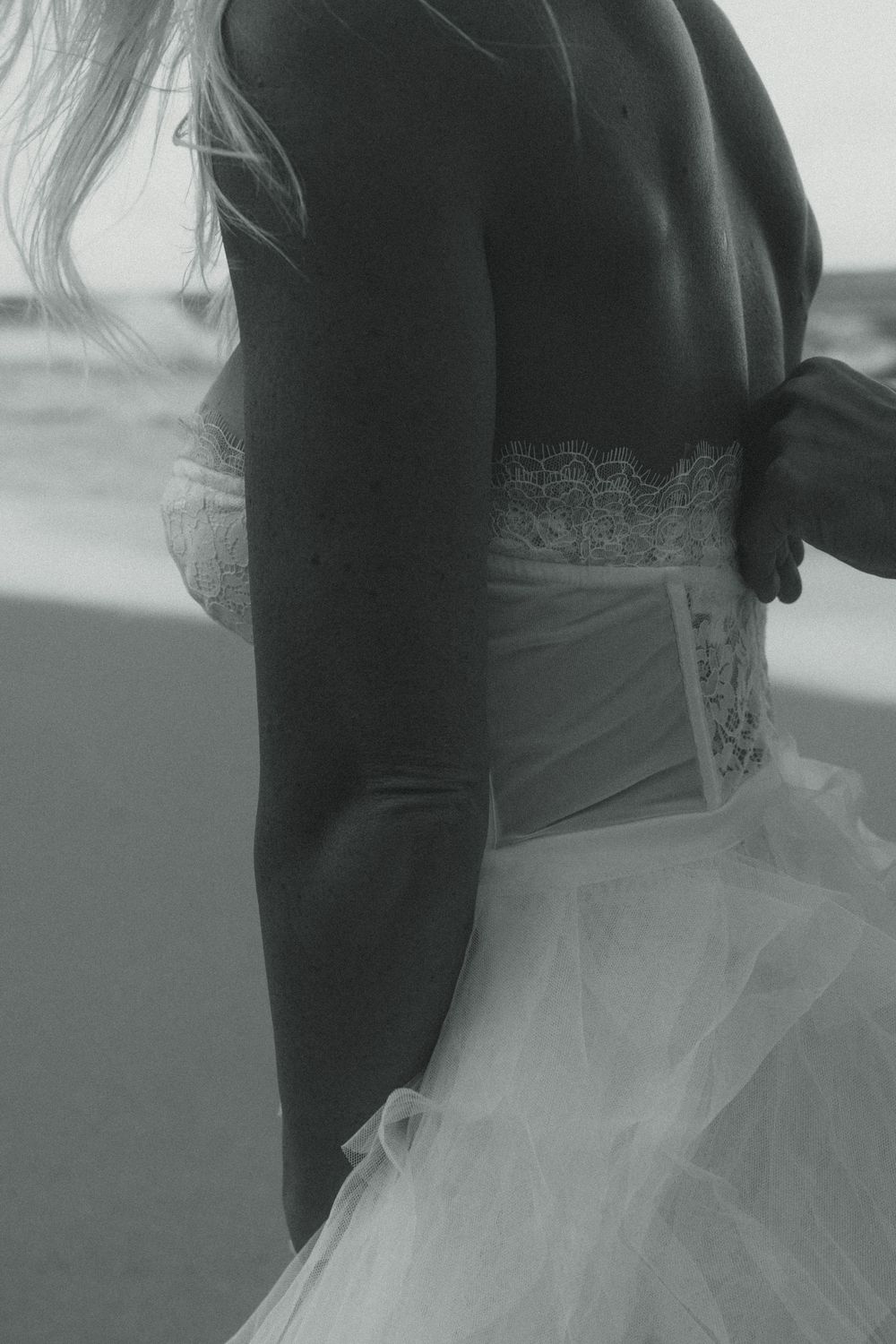 Black and white photo showing elegant lace corset detail and tulle skirt of a formal dress.
