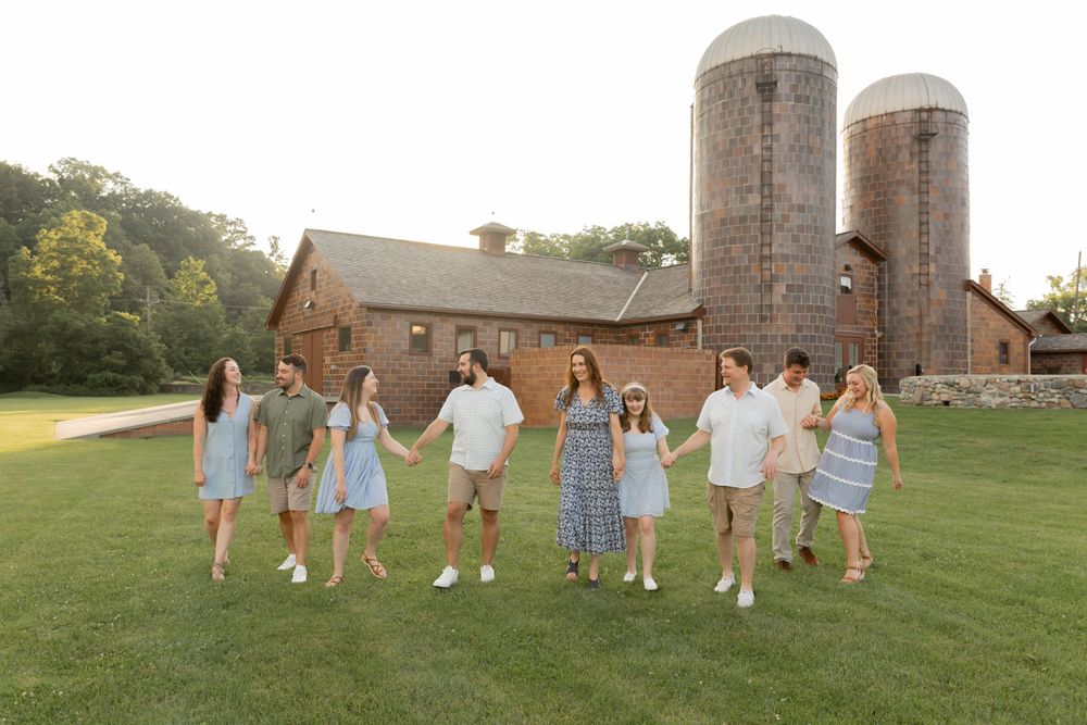family holding hands and walking in front of the farm at van hoosen farms