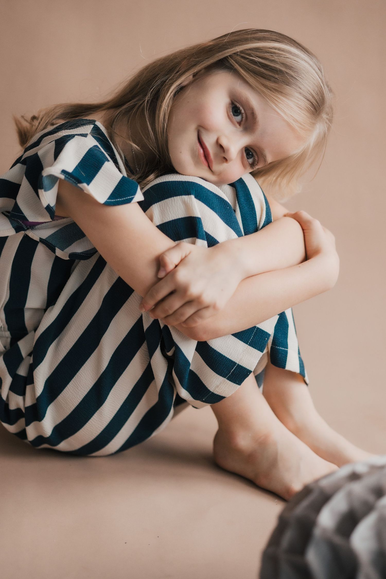 Portrait series capturing candid moments in a navy striped dress against neutral backdrop.