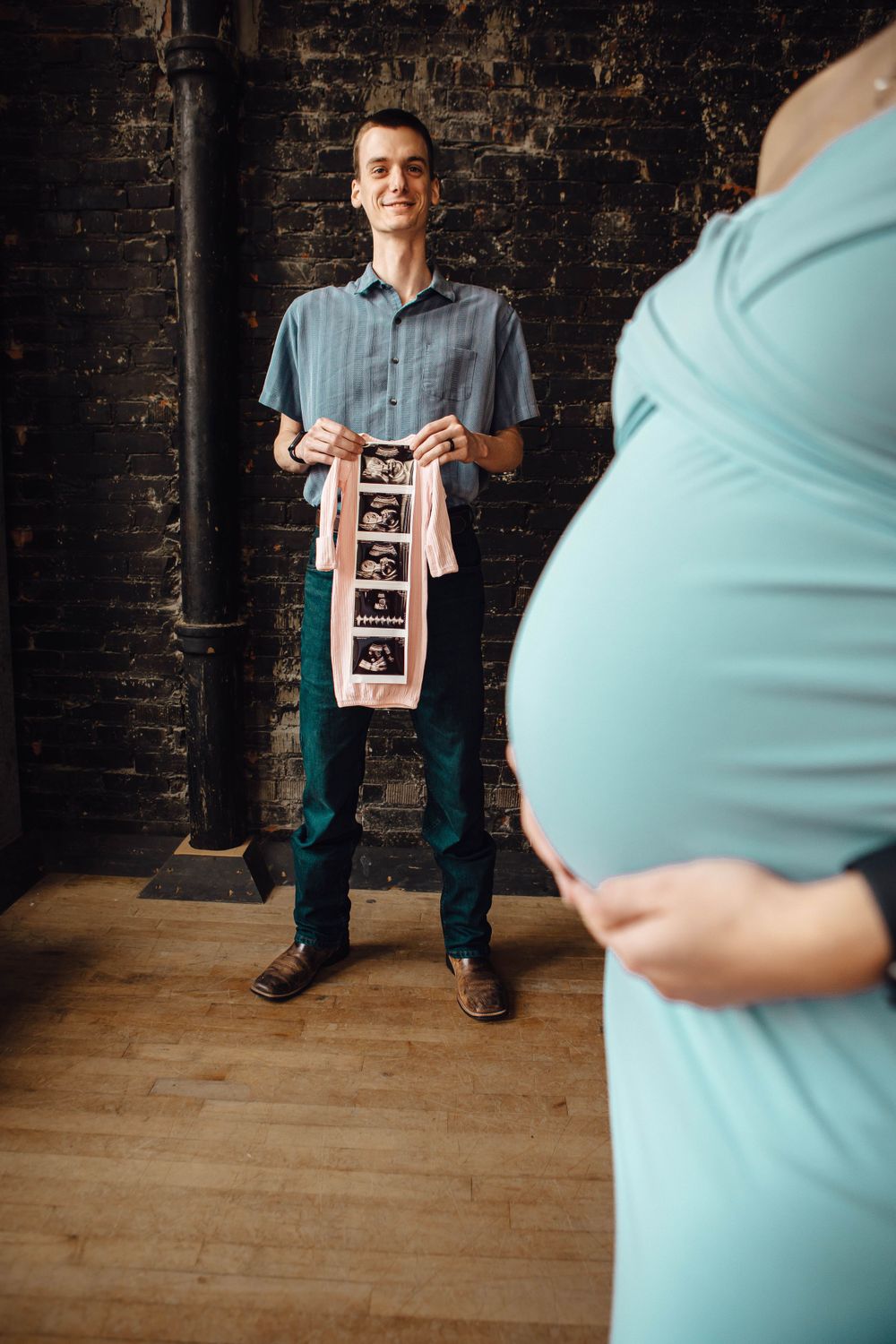 Expectant couple in a rustic setting sharing pregnancy ultrasound photos.