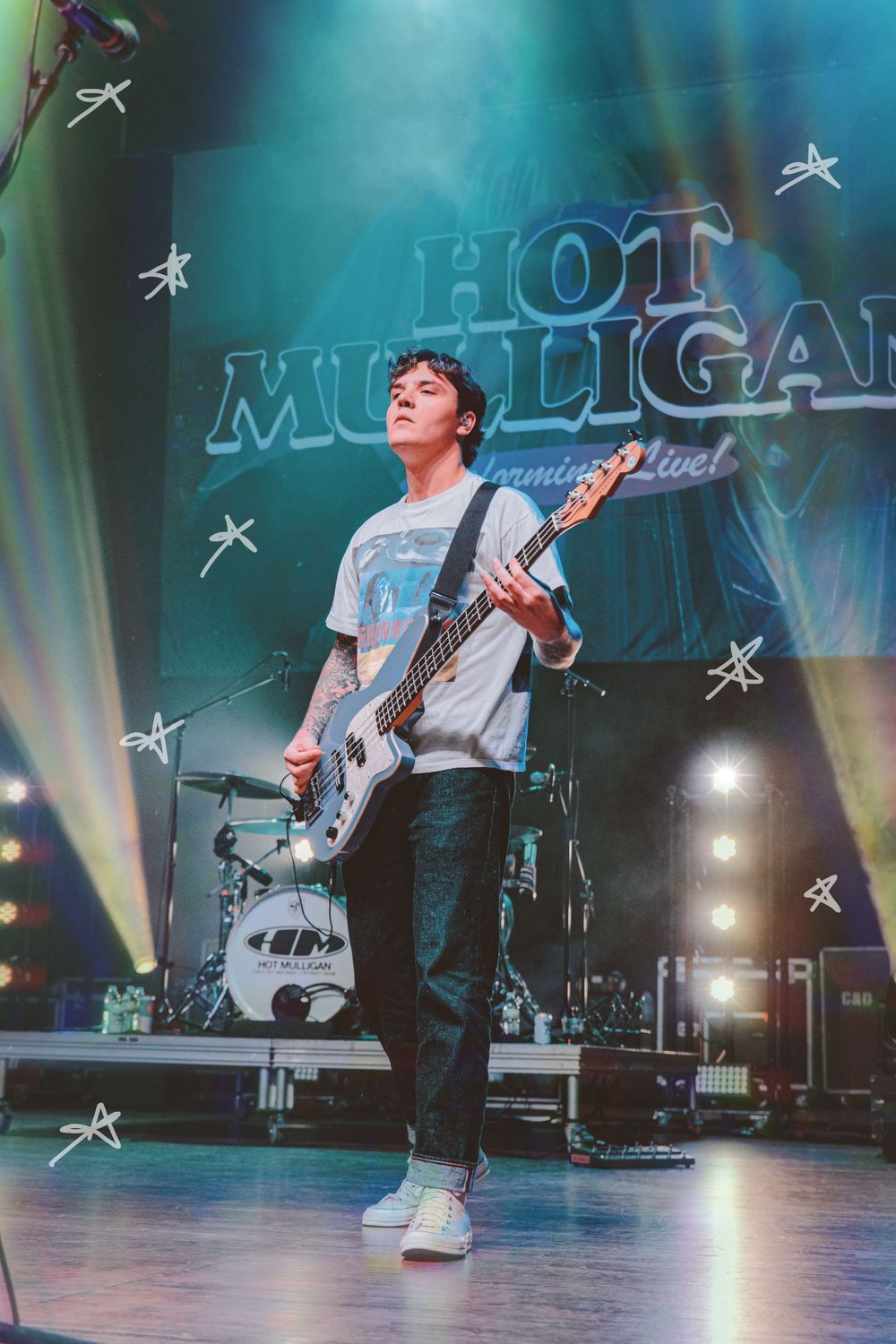 A musician plays bass guitar on stage with 'Hot Mulligan' text and star decorations in the background.