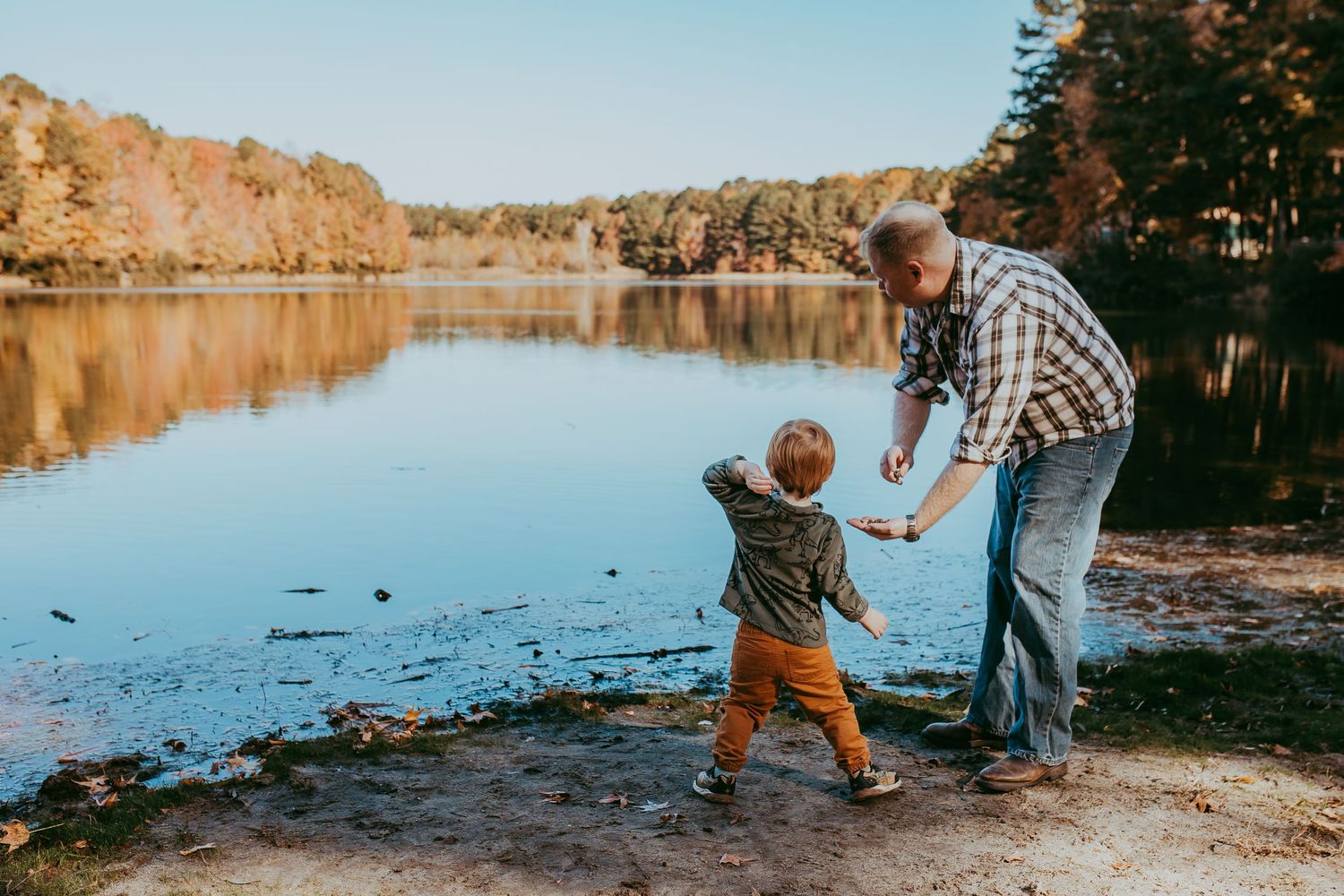 Two people enjoying a peaceful autumn day by a serene lake surrounded by fall foliage. Whitney Popp, Arizona photographer.