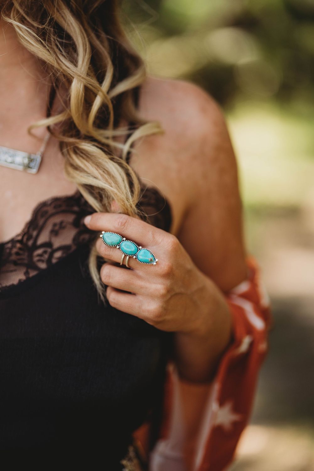 Close-up of turquoise statement ring on hand with black lace top detail.