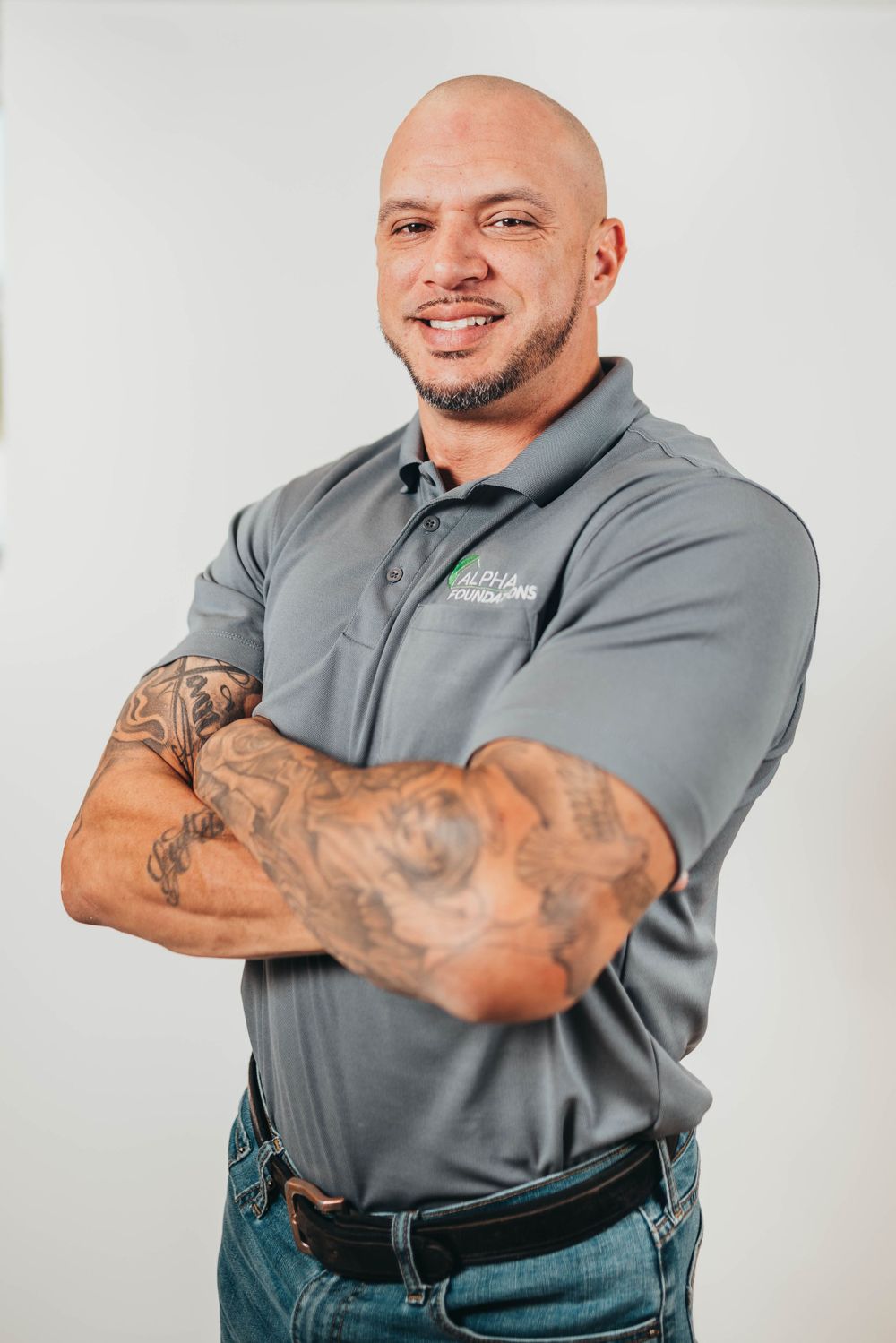 Professional portrait of employee in grey polo shirt against white background.