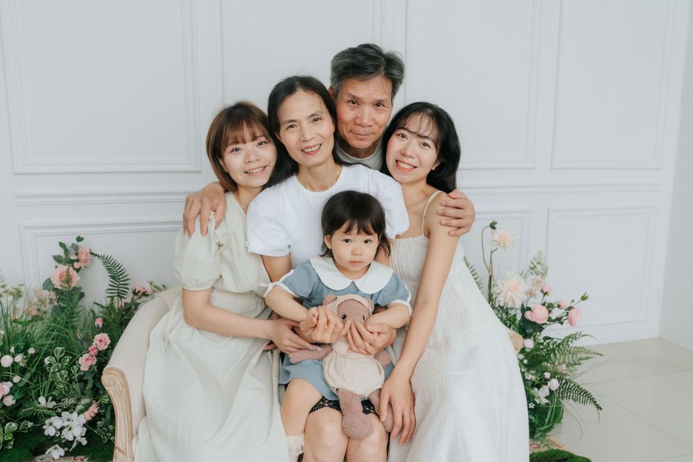Family photo session with floral arrangements against white wall.