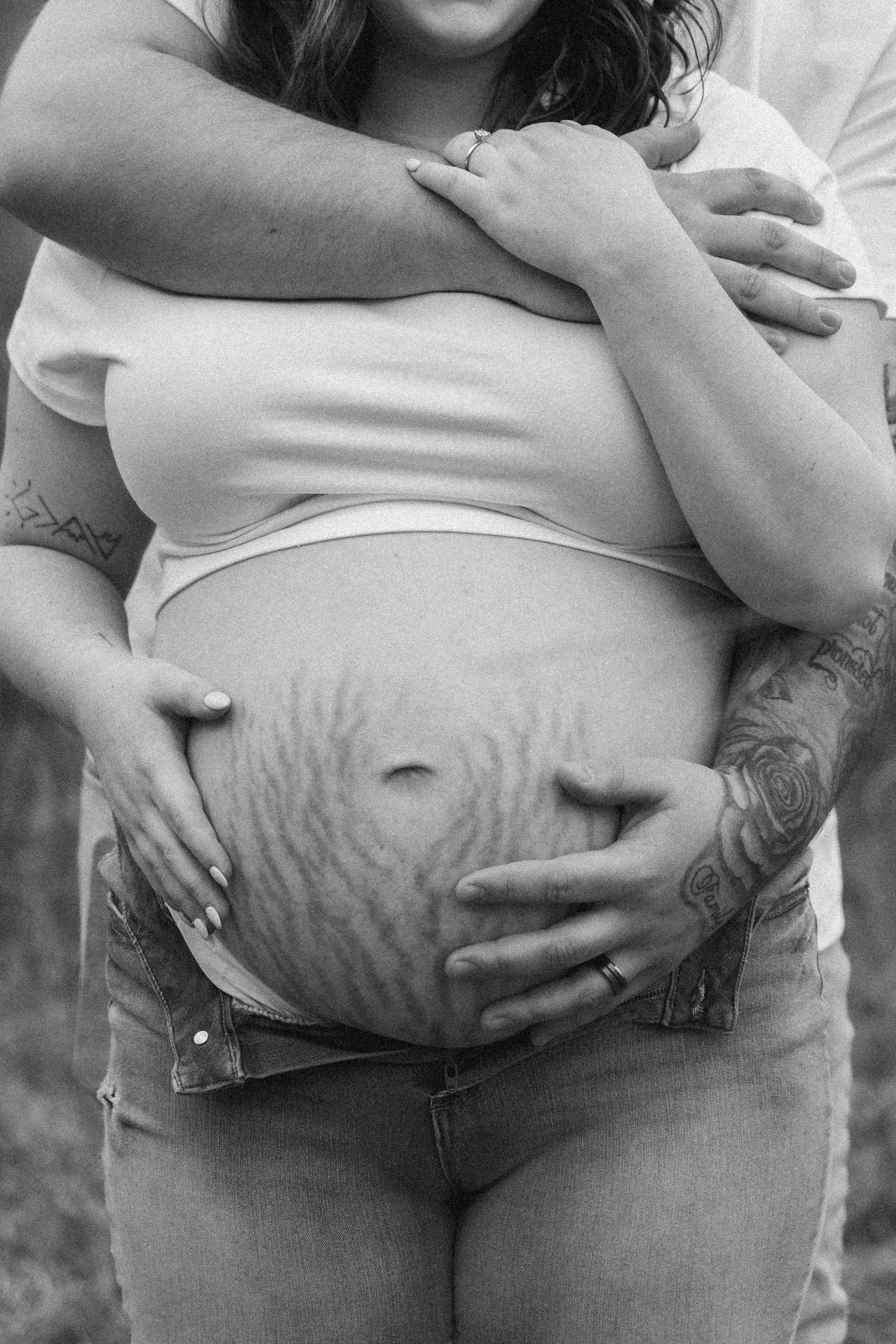 Close-up of a pregnant belly with stretch marks being lovingly held.
