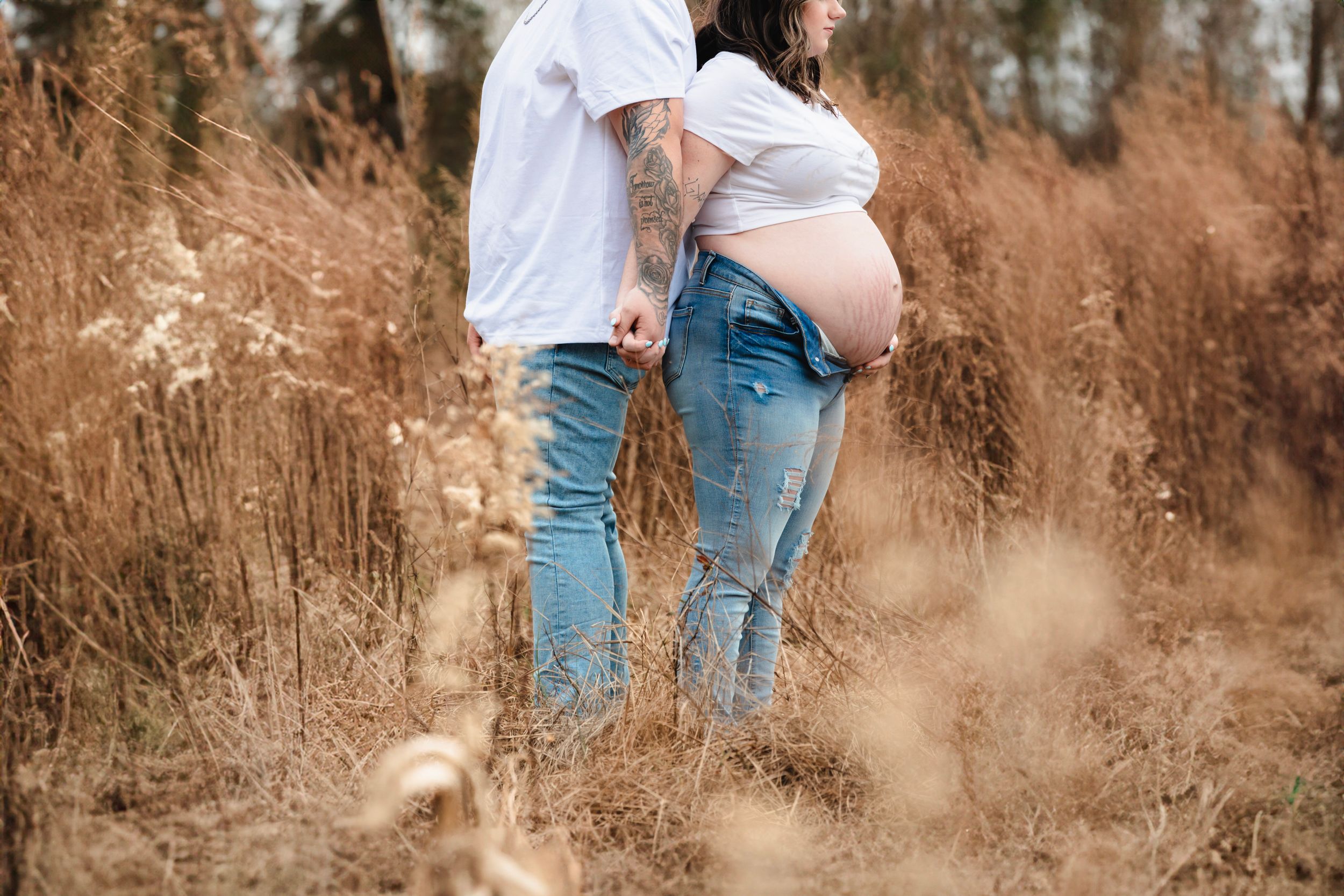 A couple shares an intimate moment during their outdoor maternity photoshoot.