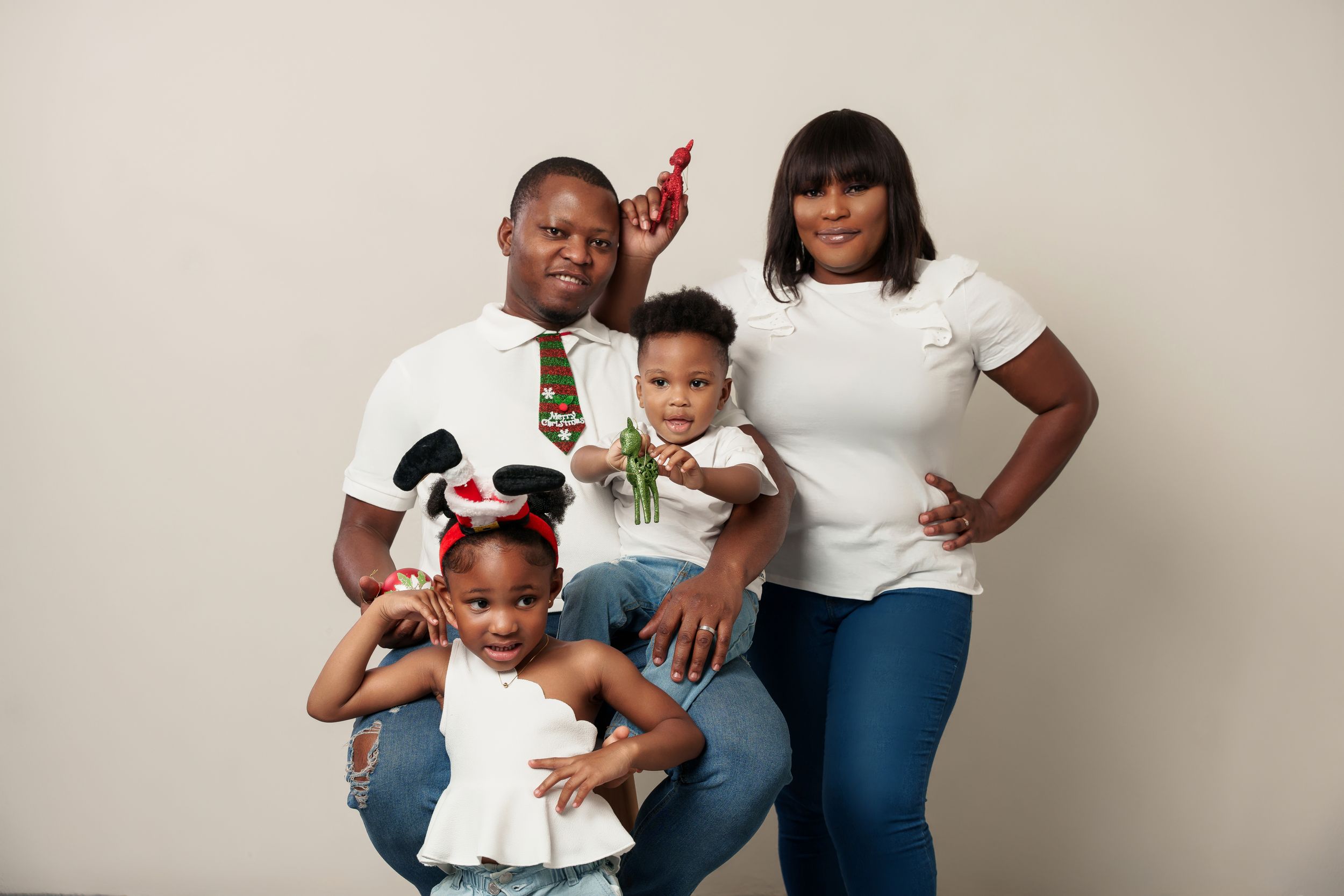 Family portrait in casual attire against a neutral studio background with festive party accessories.
