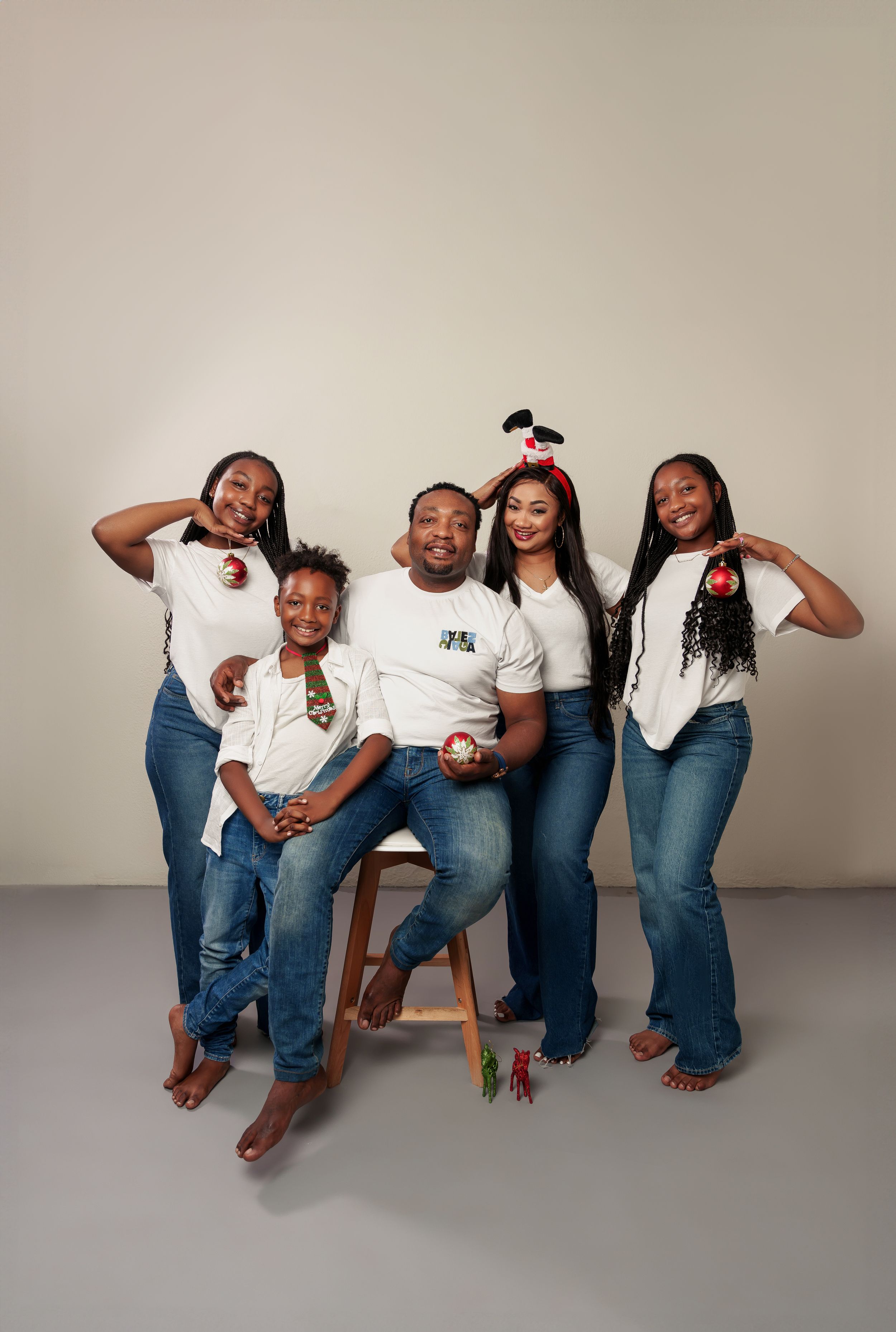Coordinated family photo with matching white shirts and blue jeans in a studio setting.