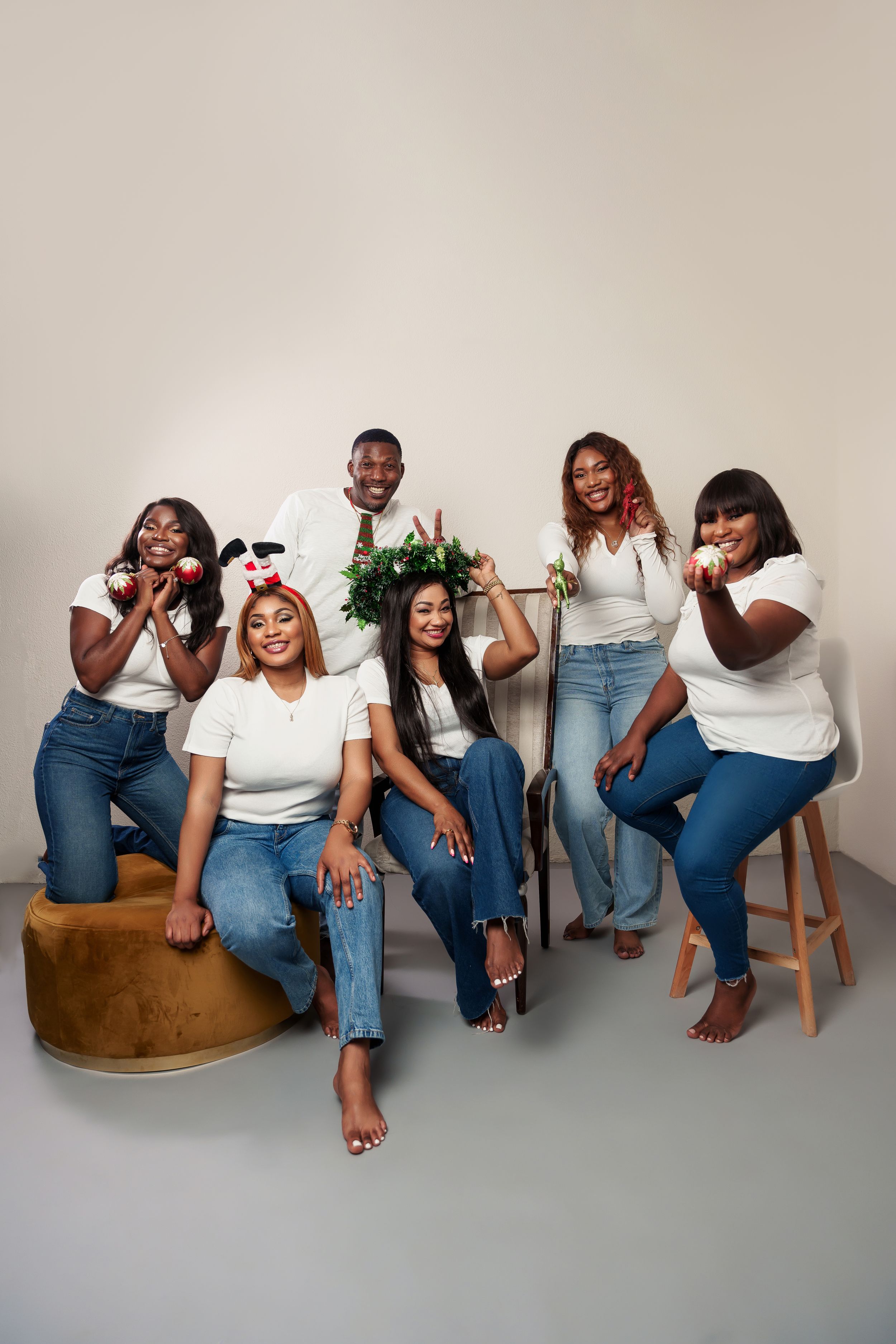 Group photo of women in matching white tops and jeans seated on brown furniture.
