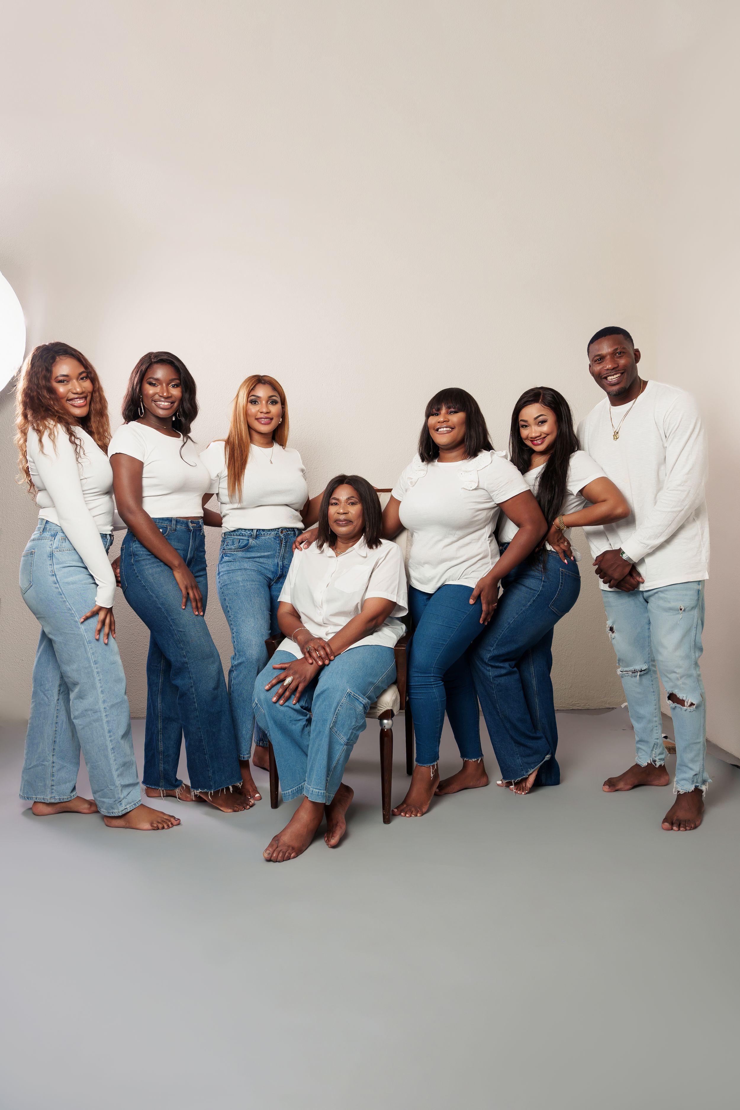 Group portrait with coordinated white tops and blue jeans in a studio setting.