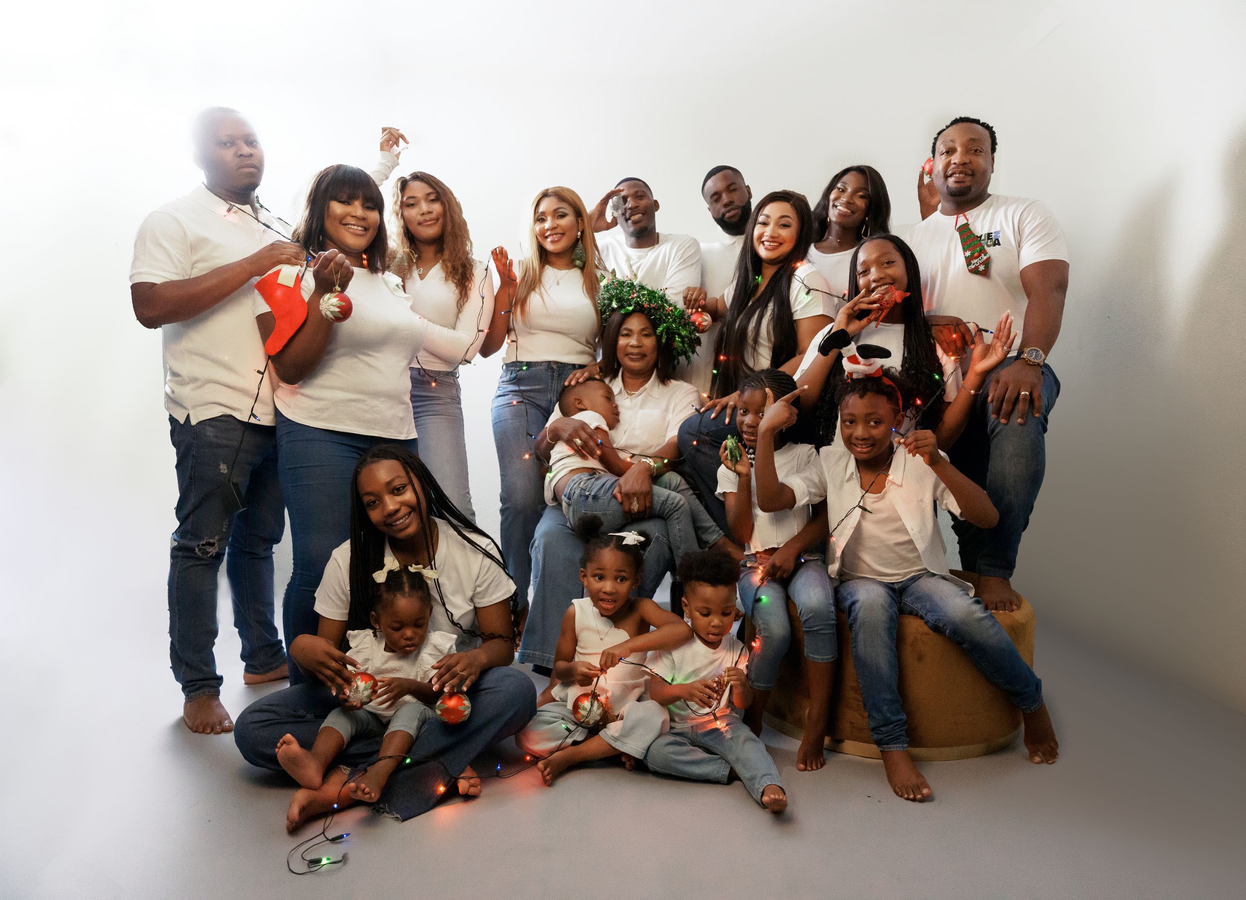 Large family group photo with multiple generations in coordinated outfits against white background.