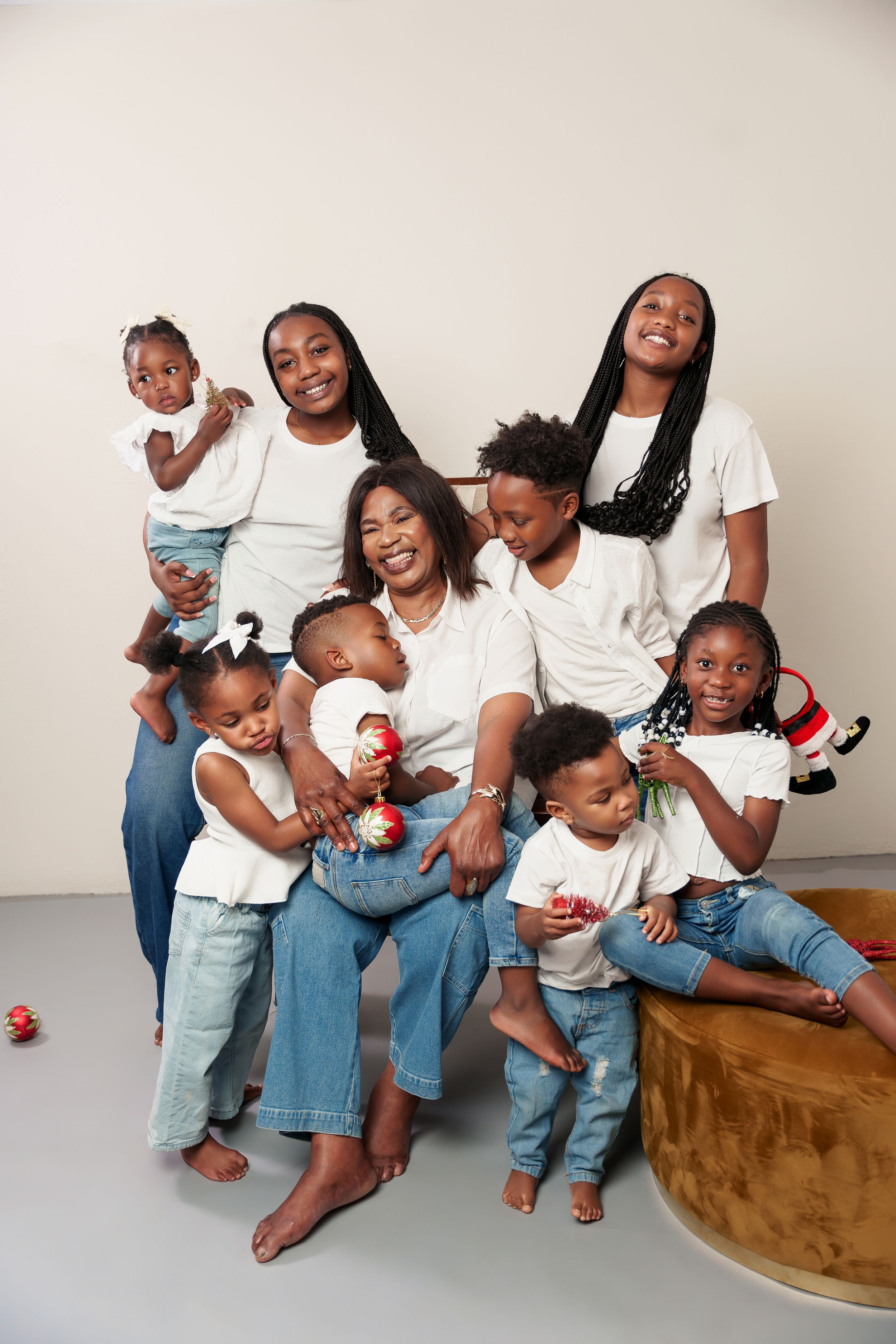 Extended family studio portrait with multiple generations in coordinated white tops and denim.