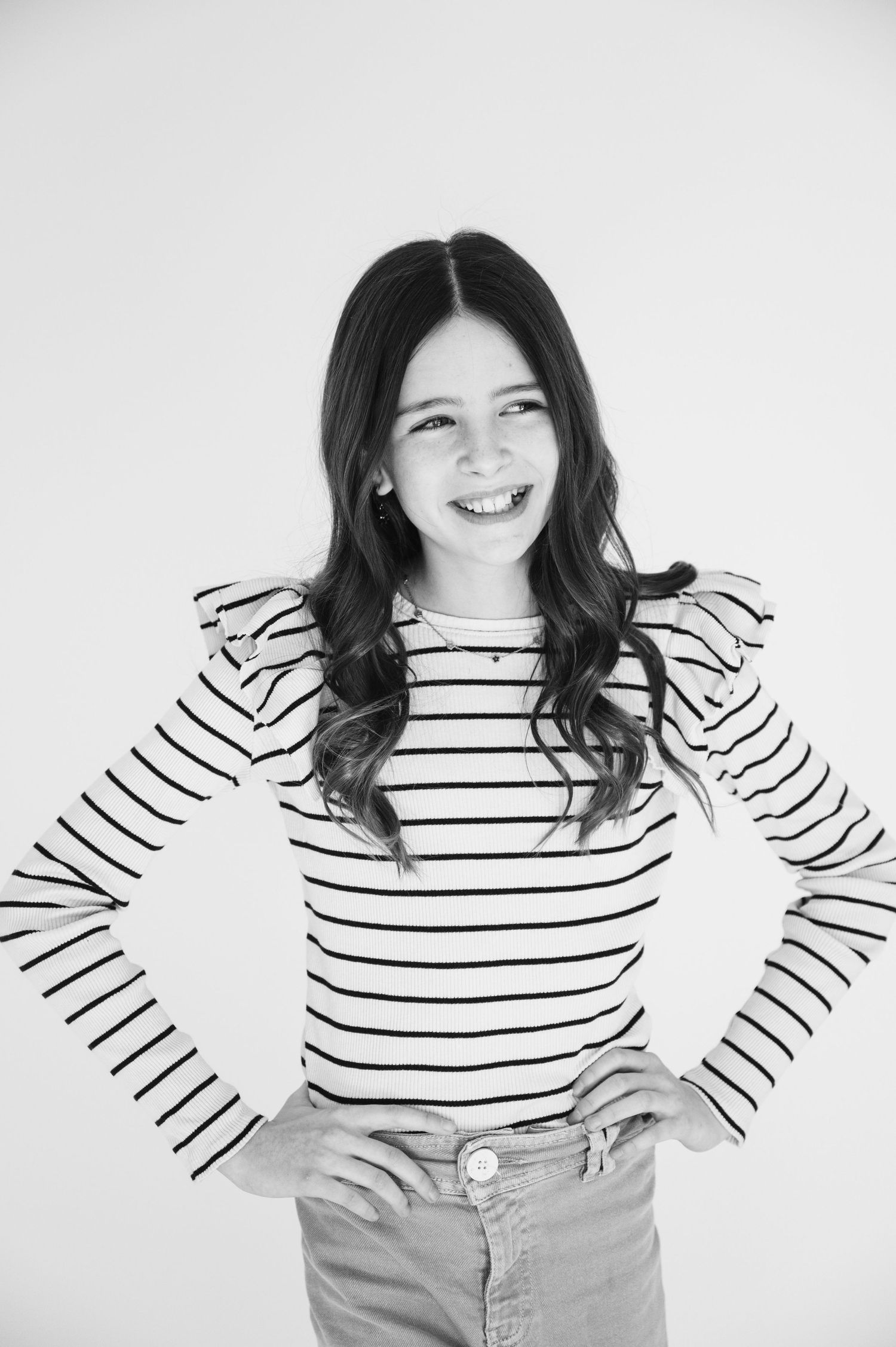 Portrait of person in striped long sleeve shirt posing with hands on hips and laughing.