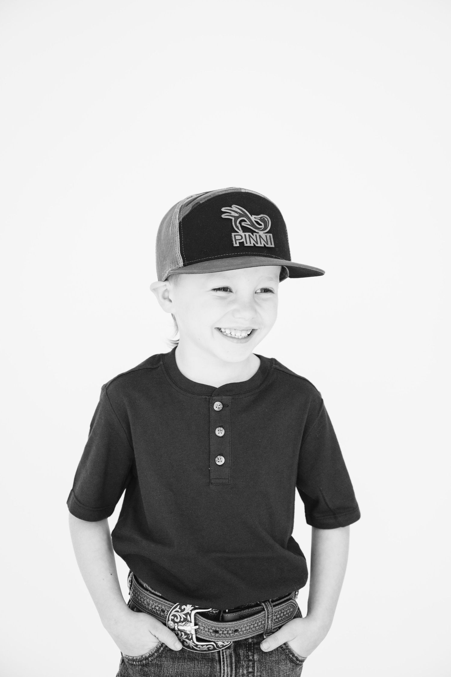 Black and white portrait of young person wearing baseball cap and henley shirt.