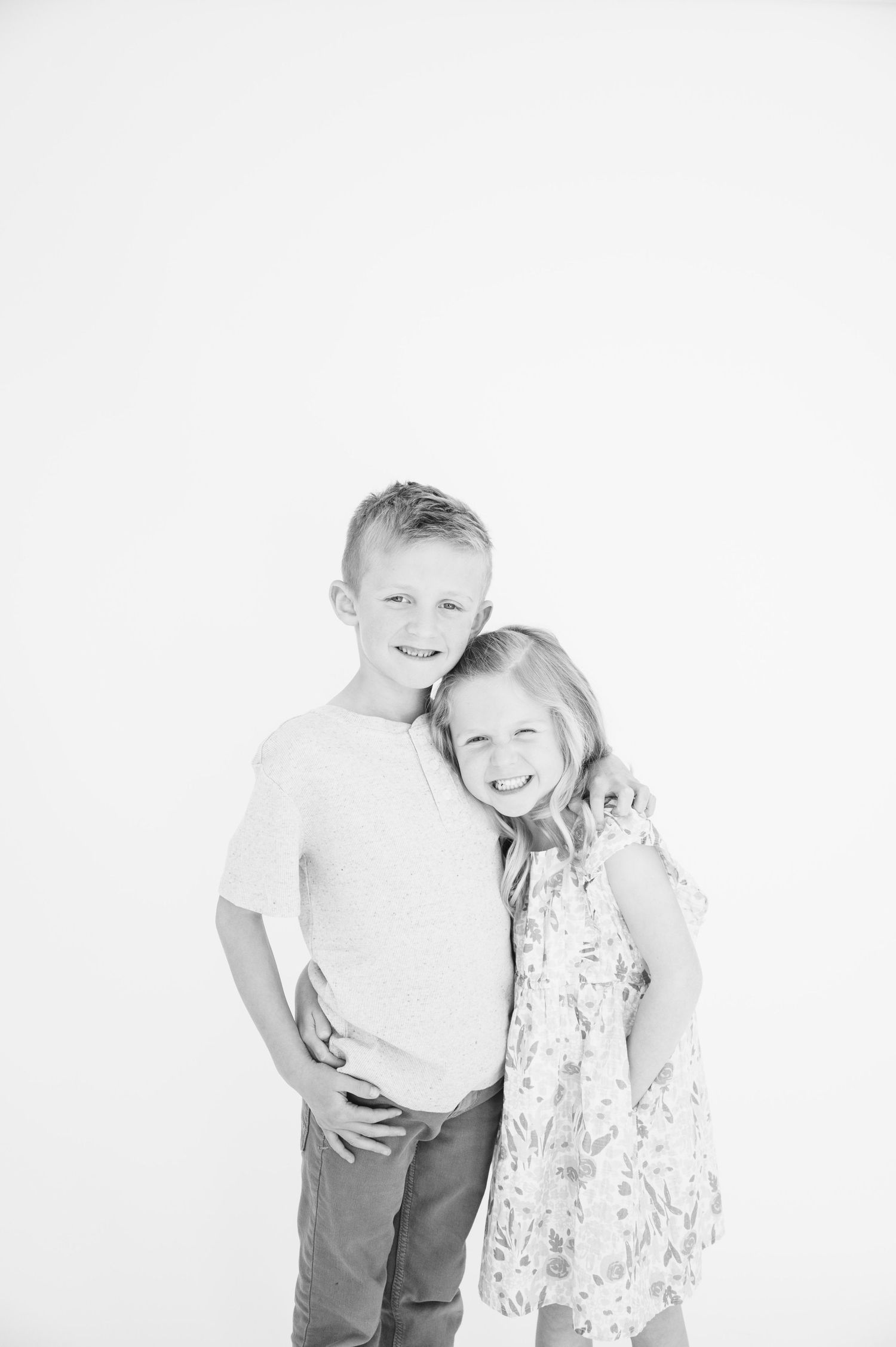 Black and white portrait of two children posing together and smiling.