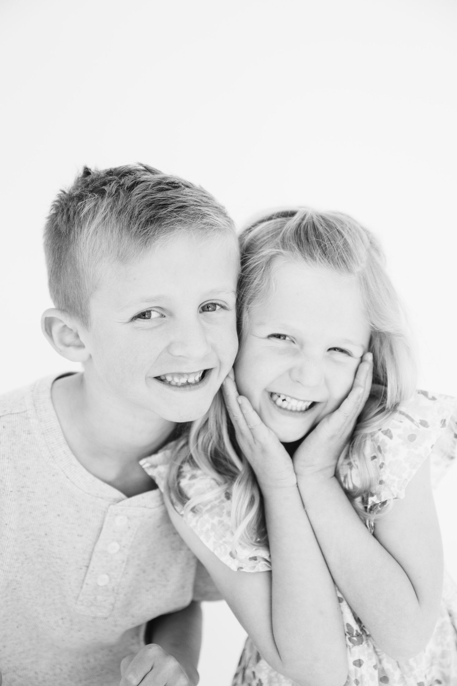 Black and white close-up of two children sharing affectionate moment together.