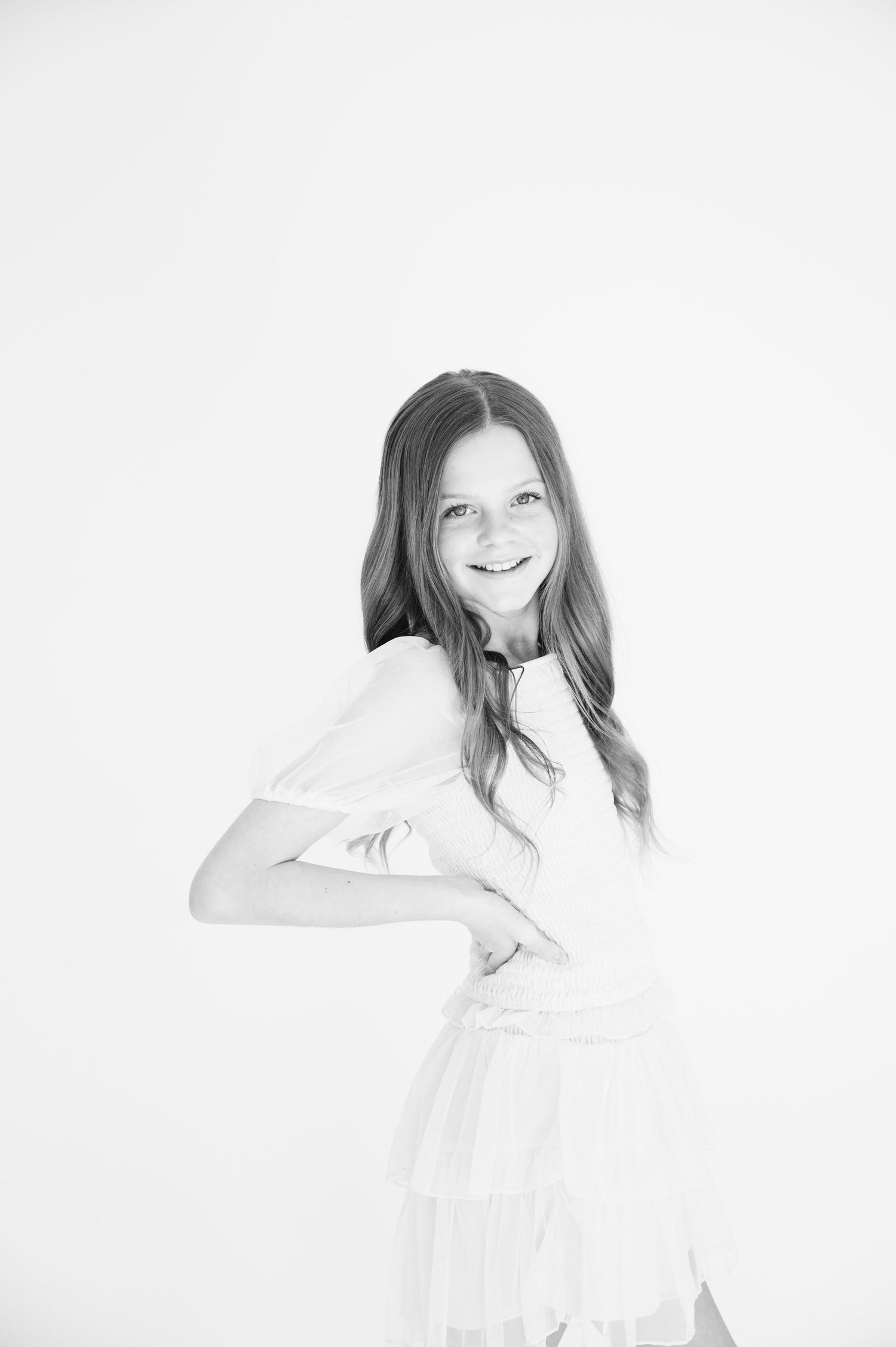 High key black and white portrait showing a joyful twirl in a white dress.