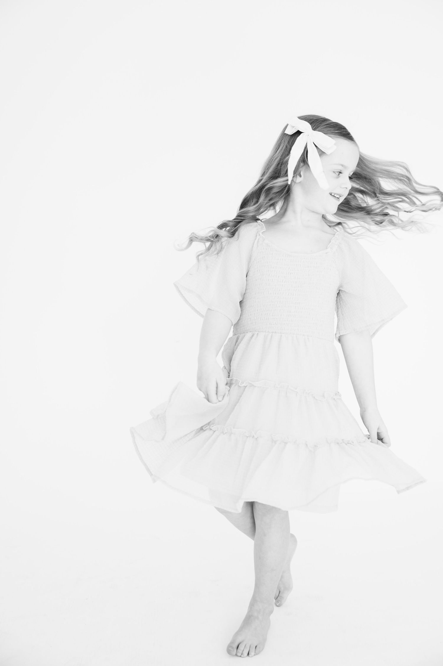 Artistic black and white photo capturing movement with flowing dress and hair.