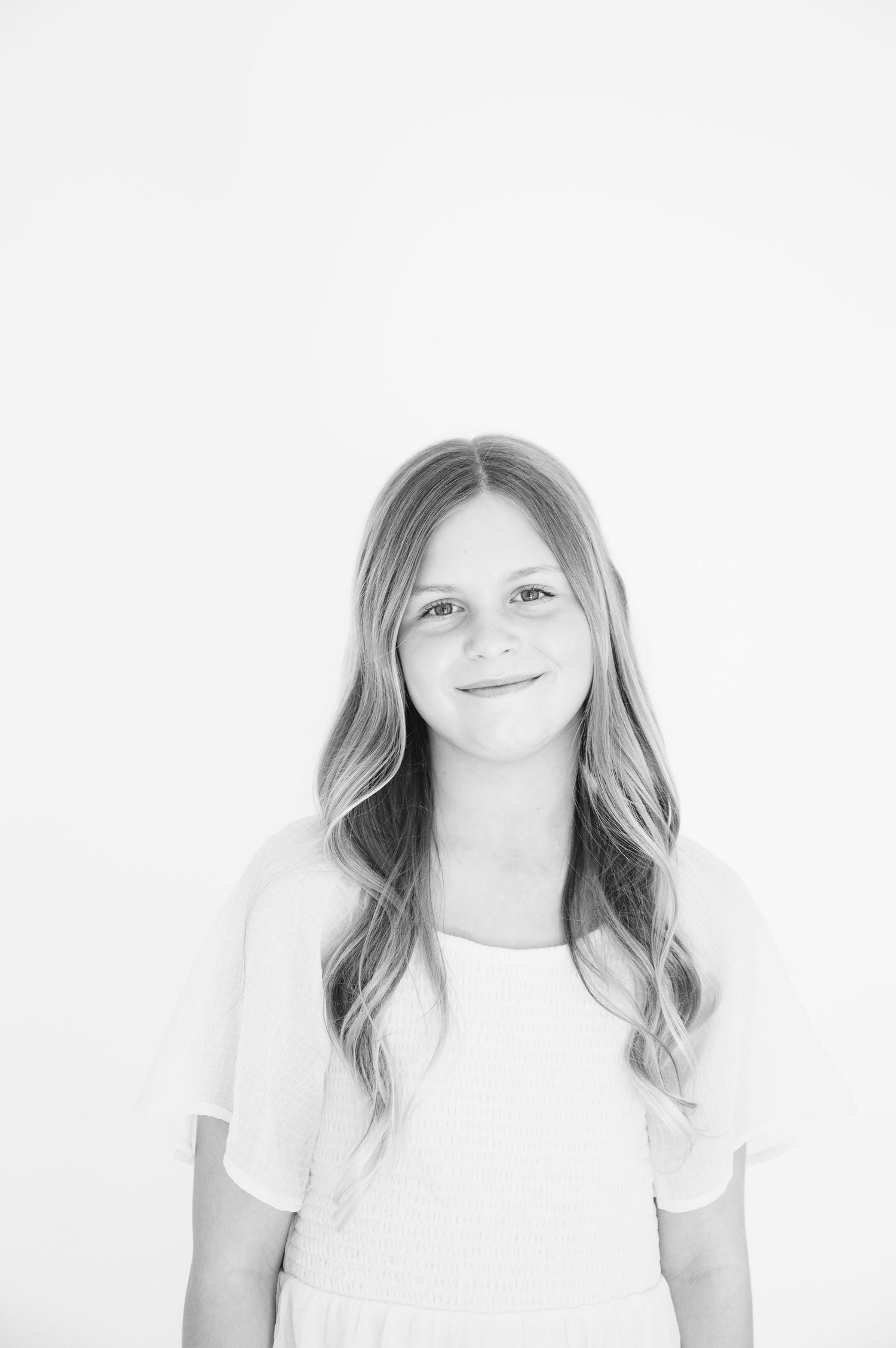 Minimalist black and white headshot with soft lighting and gentle expression.
