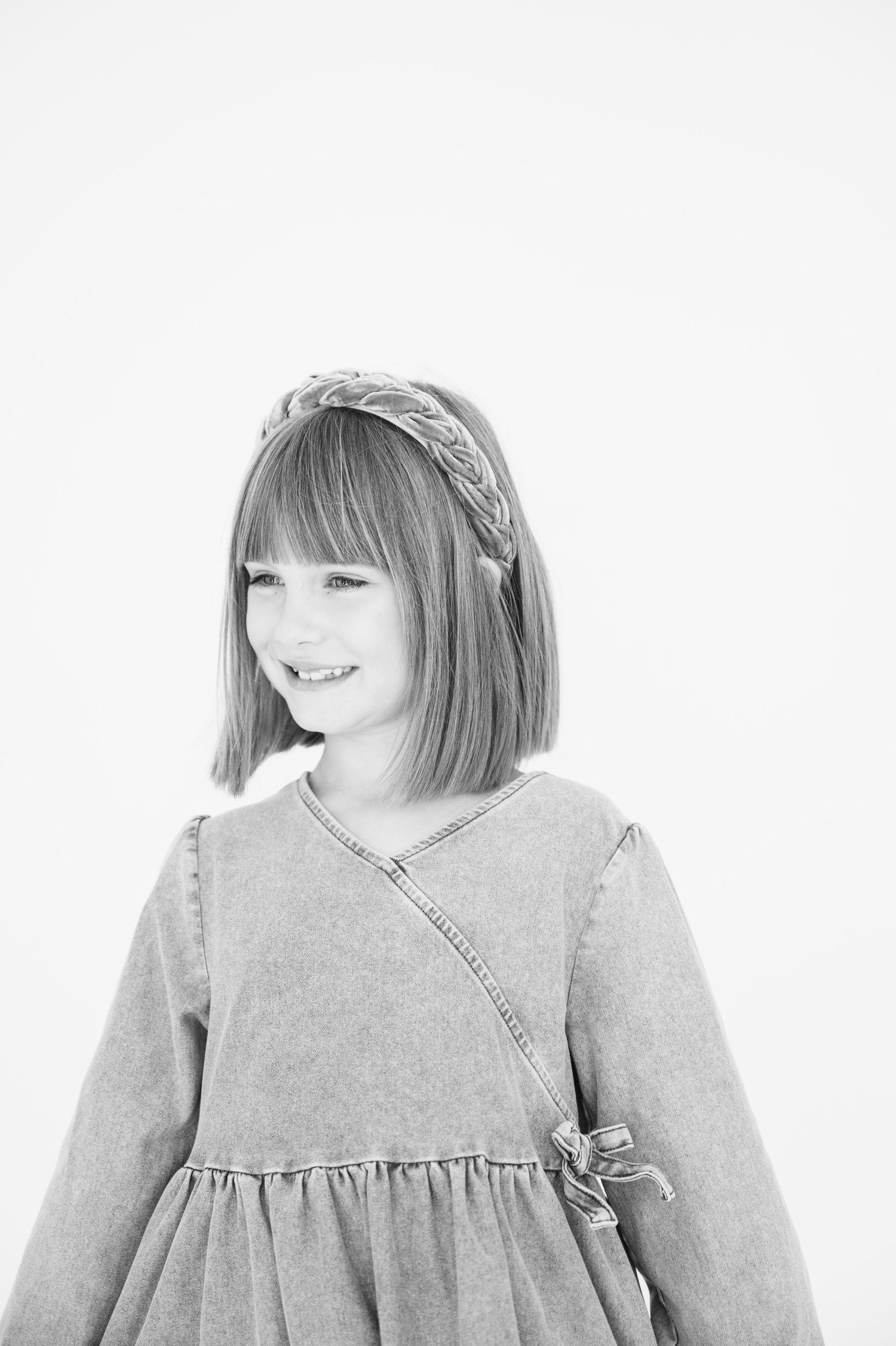 Black and white portrait showcasing braided headband and wrap-style dress.