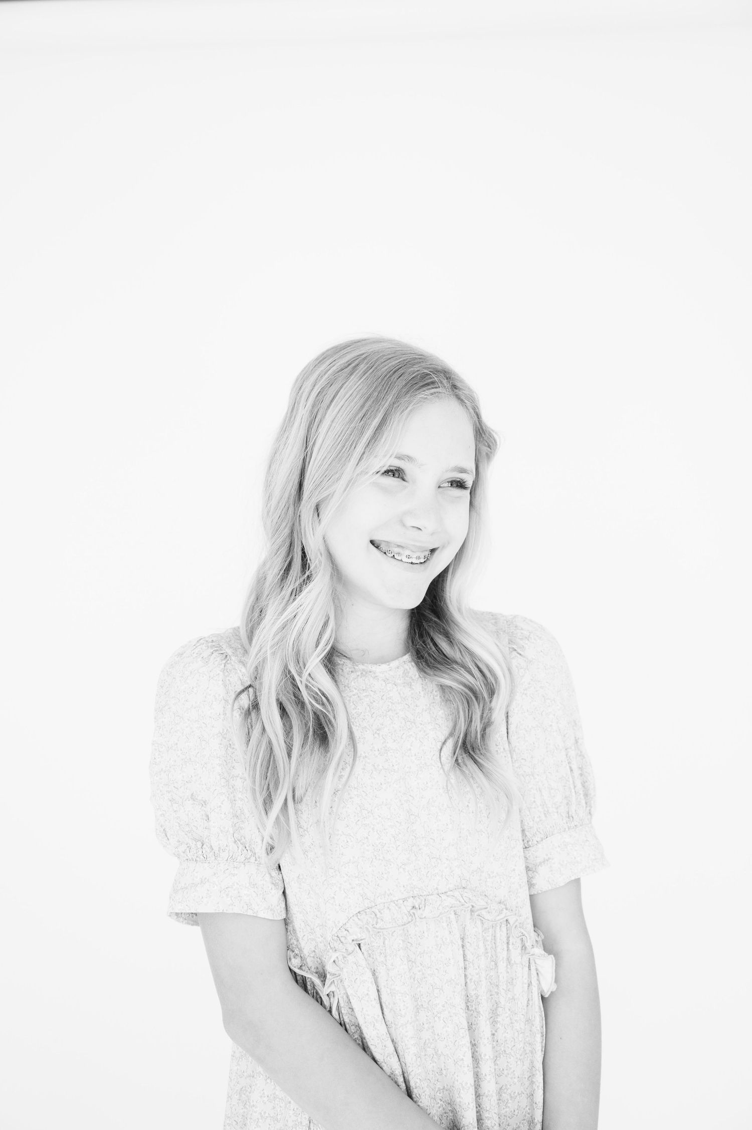 High key black and white portrait with natural smile and flowing hair.