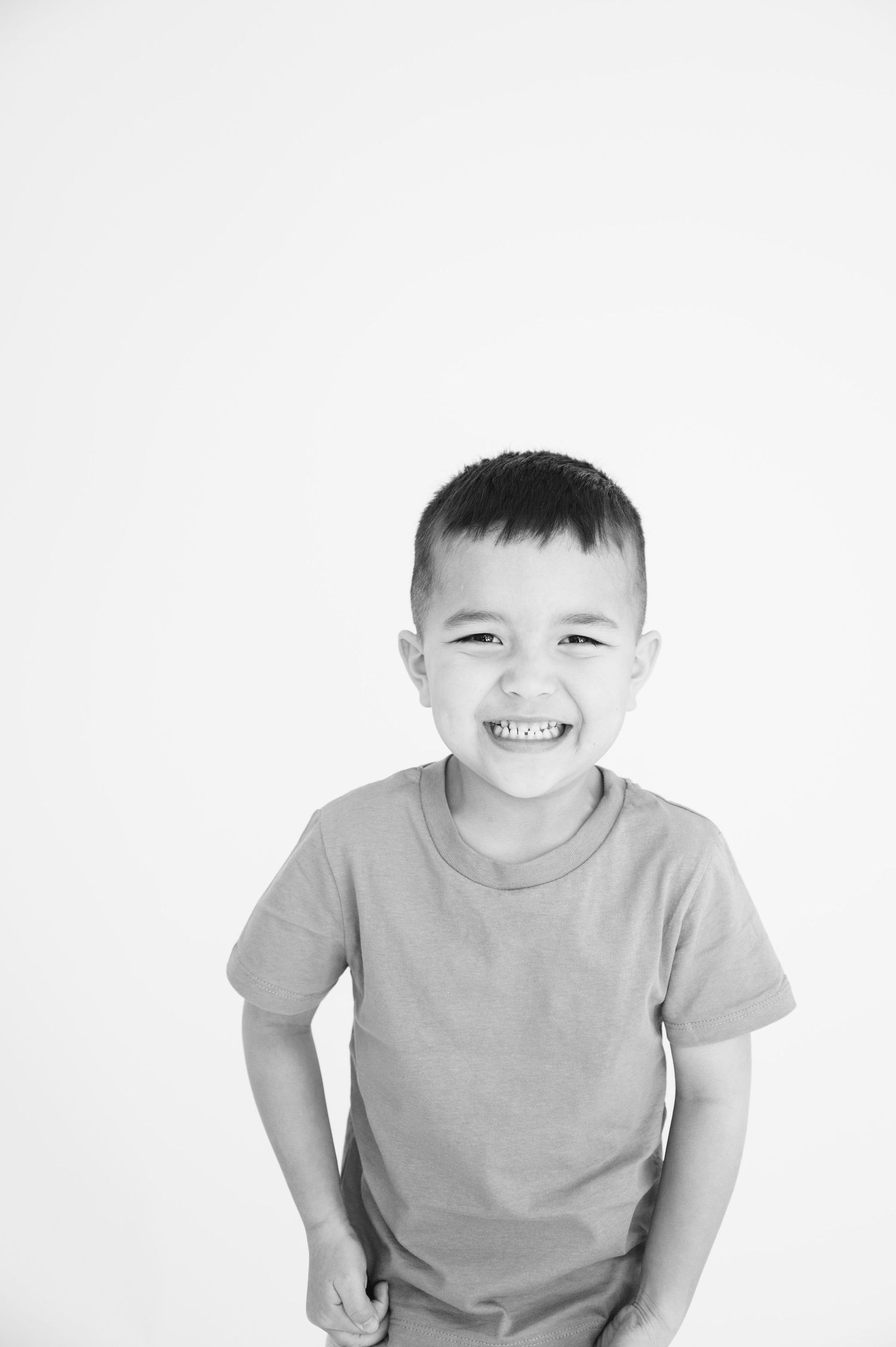 Black and white portrait of a joyful young child wearing a t-shirt against a white background.