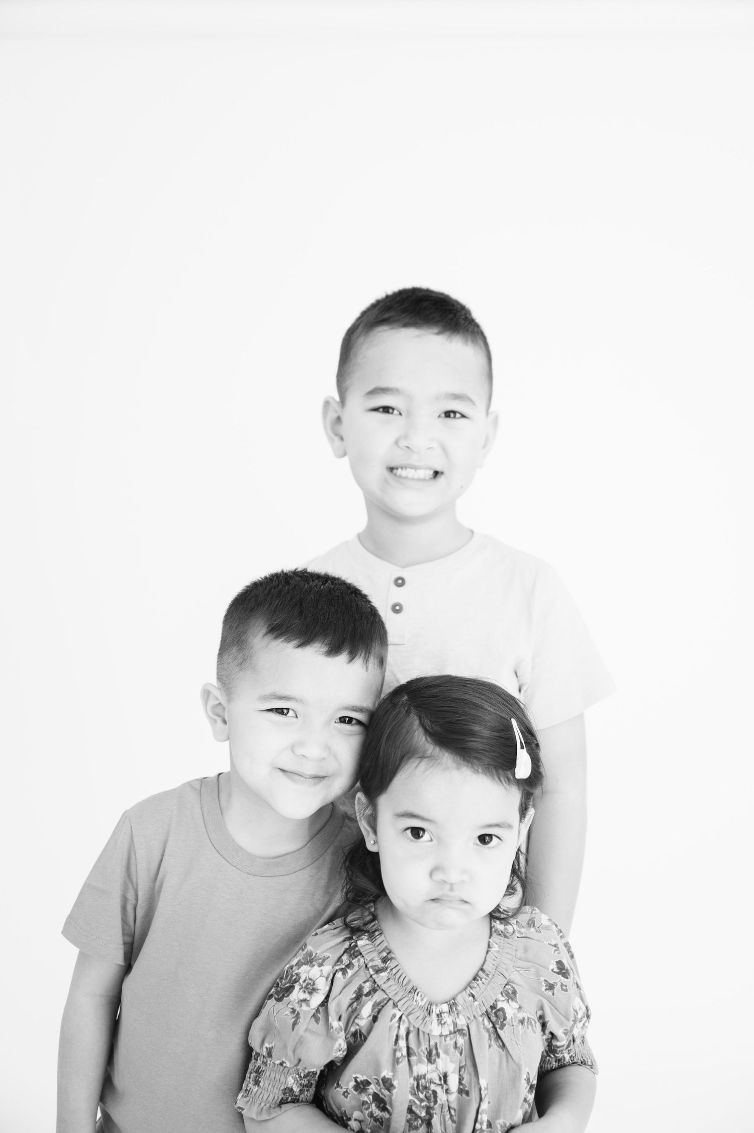 Black and white studio portrait of three children against white background.