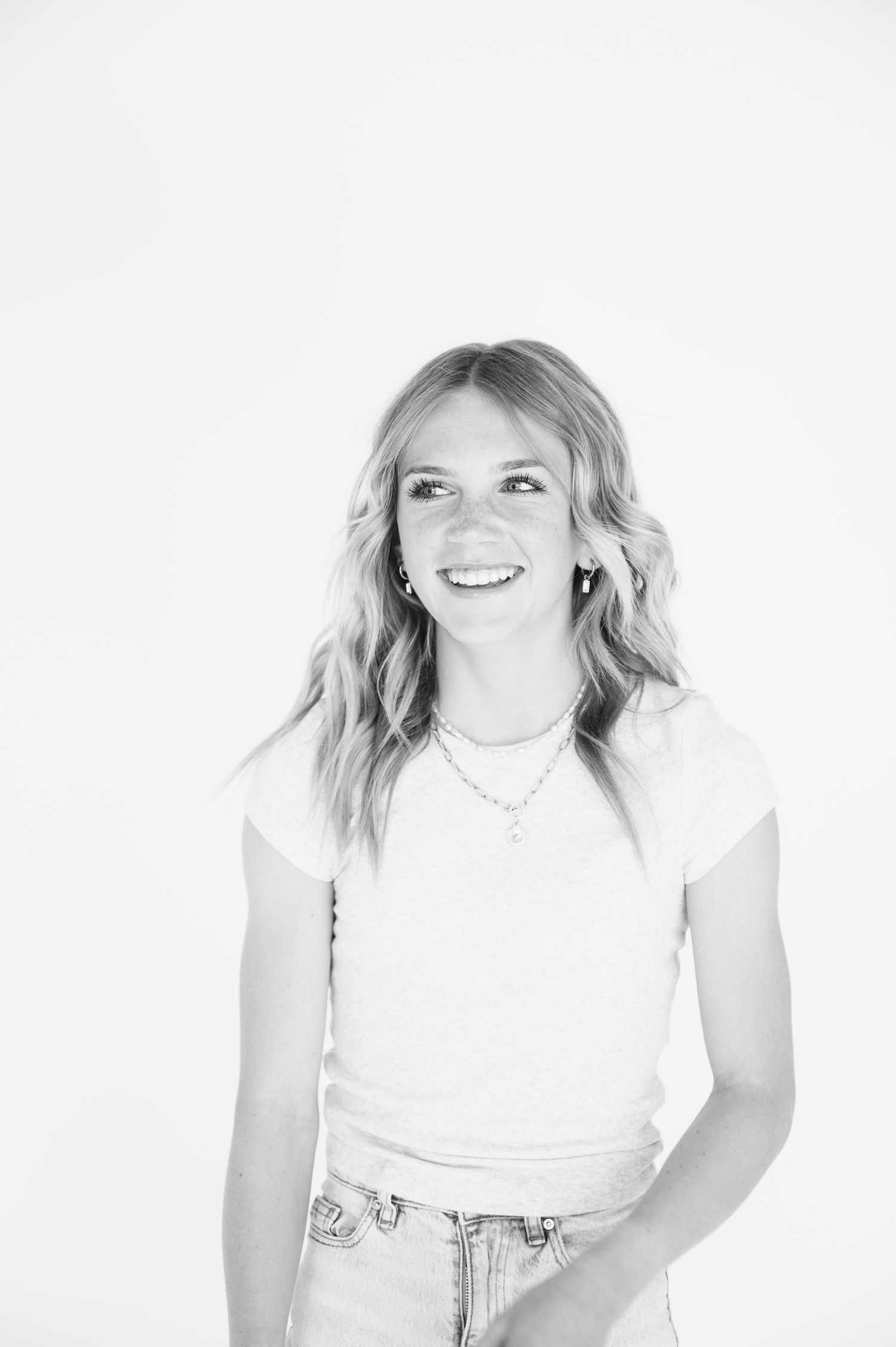 Black and white portrait of a woman in white t-shirt and jeans against white background.