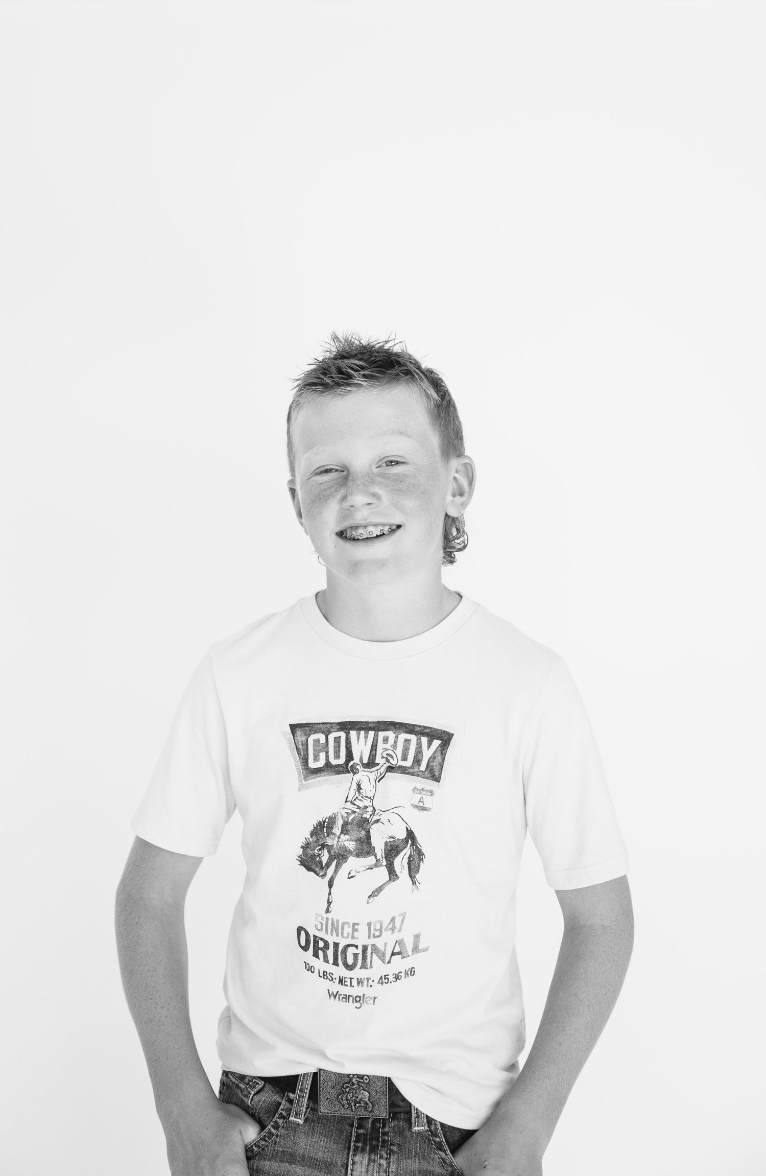 Black and white portrait of a boy wearing Cowboy Original graphic t-shirt.