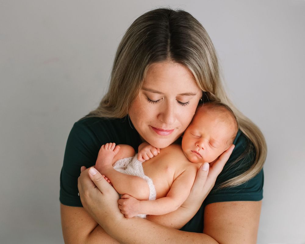 A tender moment between mother and newborn baby as they embrace photographed by Jillian Kennedy