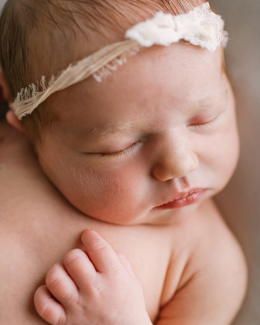 Sleeping newborn baby wearing delicate white lace headband in soft natural light portrait by Jillian Kennedy