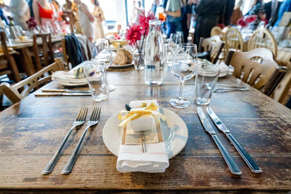 Elegant place setting with white napkin, silverware and botanical decoration on wooden table.